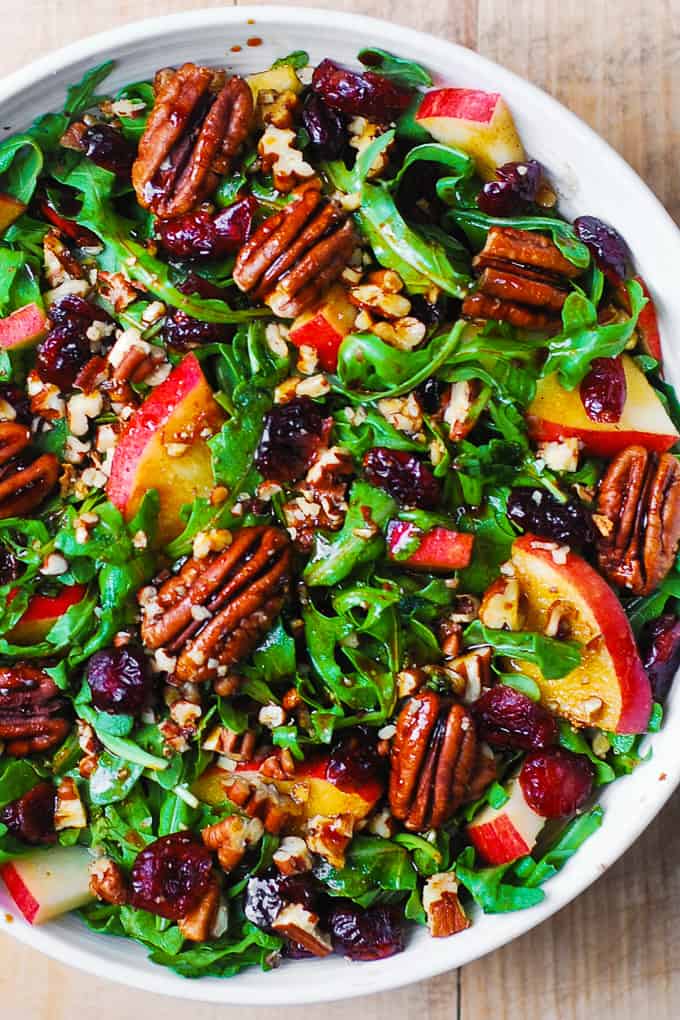 Arugula Salad with Apples, Cranberries, and Pecans in a white bowl.