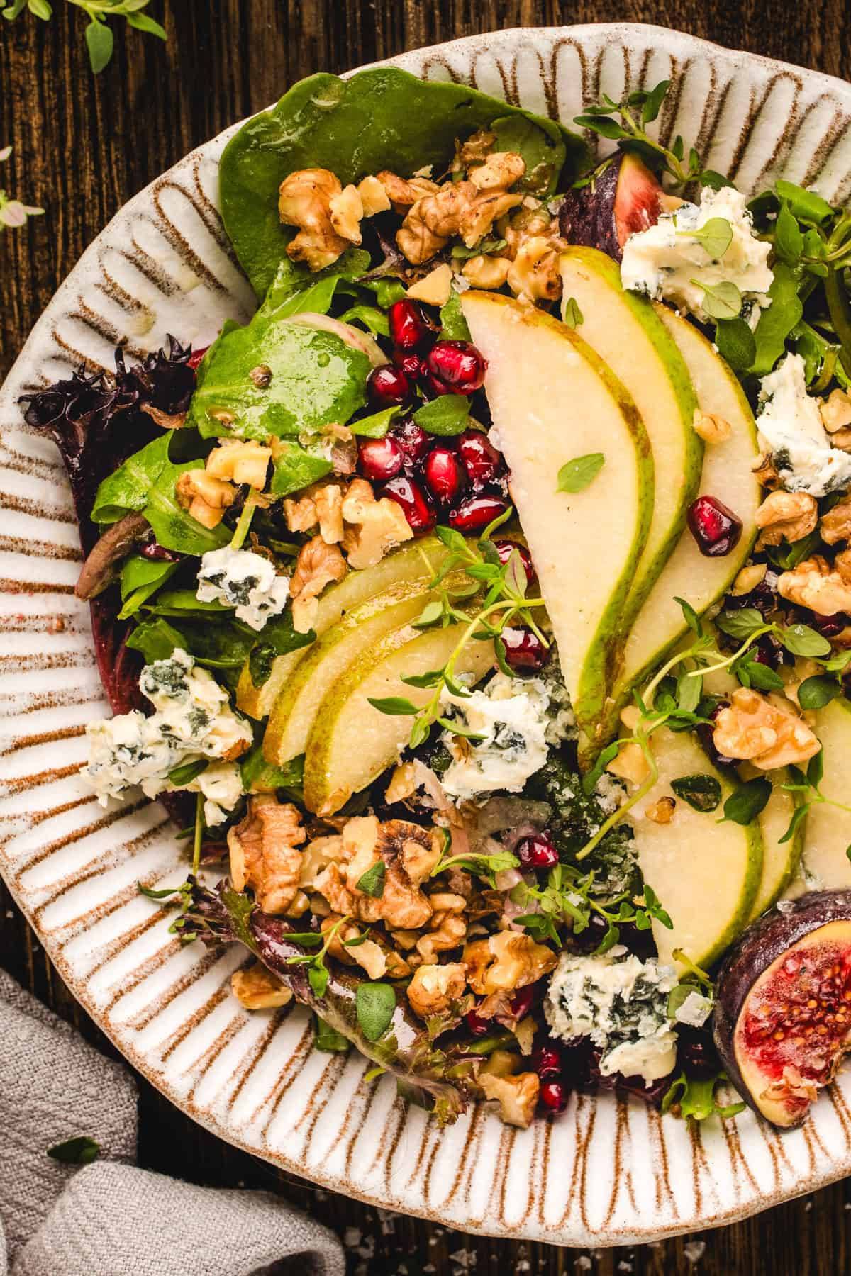Pear Salad with Walnuts and Honey-Mustard Dressing on a white plate.