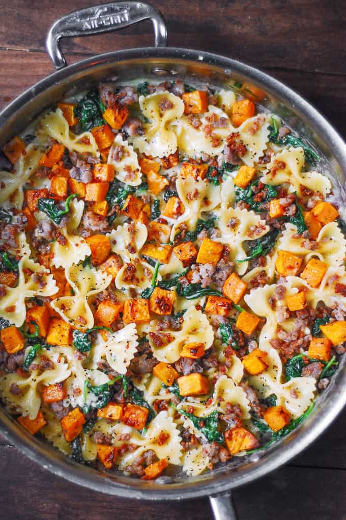 Creamy Butternut Squash Pasta with Sausage and Spinach in a stainless steel pan.