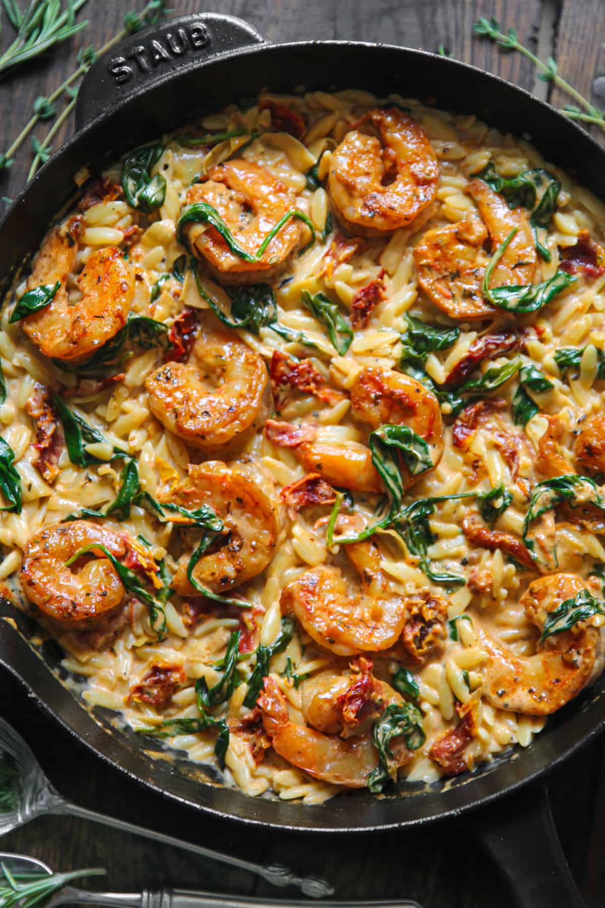 Tuscan Shrimp Orzo with Spinach, Sun-Dried Tomatoes, and Artichokes - in a cast iron pan.