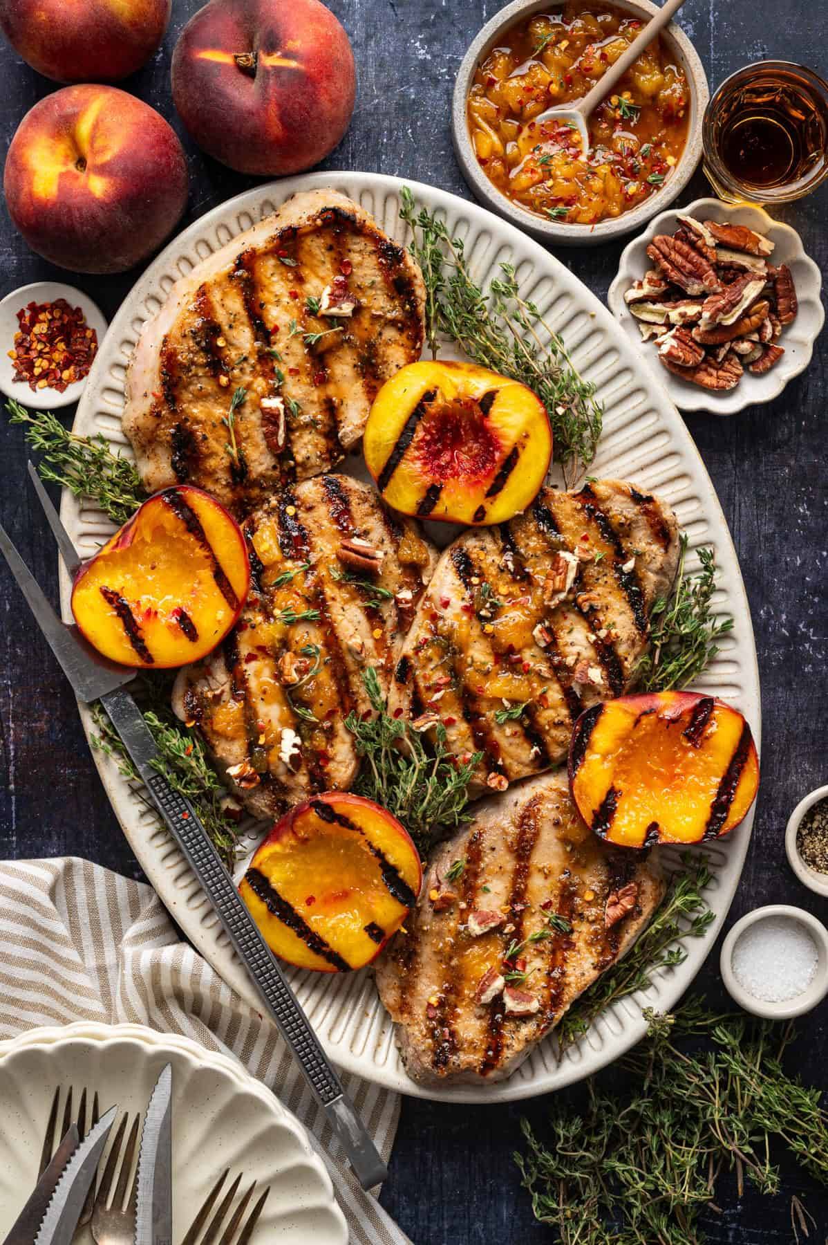Glazed Pork Chops with Peaches and Bourbon Glaze on a white platter.