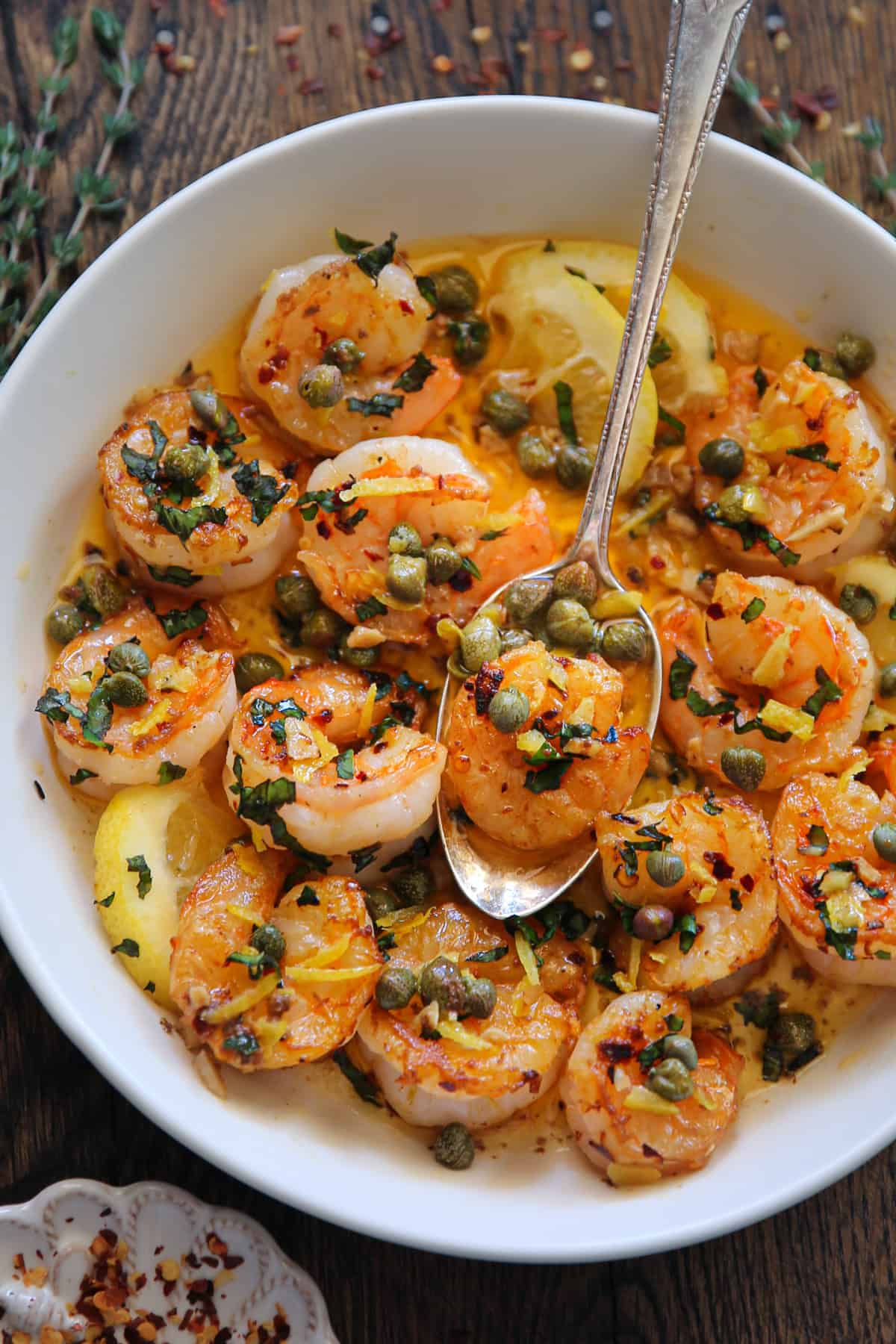 Shrimp Scampi with capers and lemon in a white bowl.