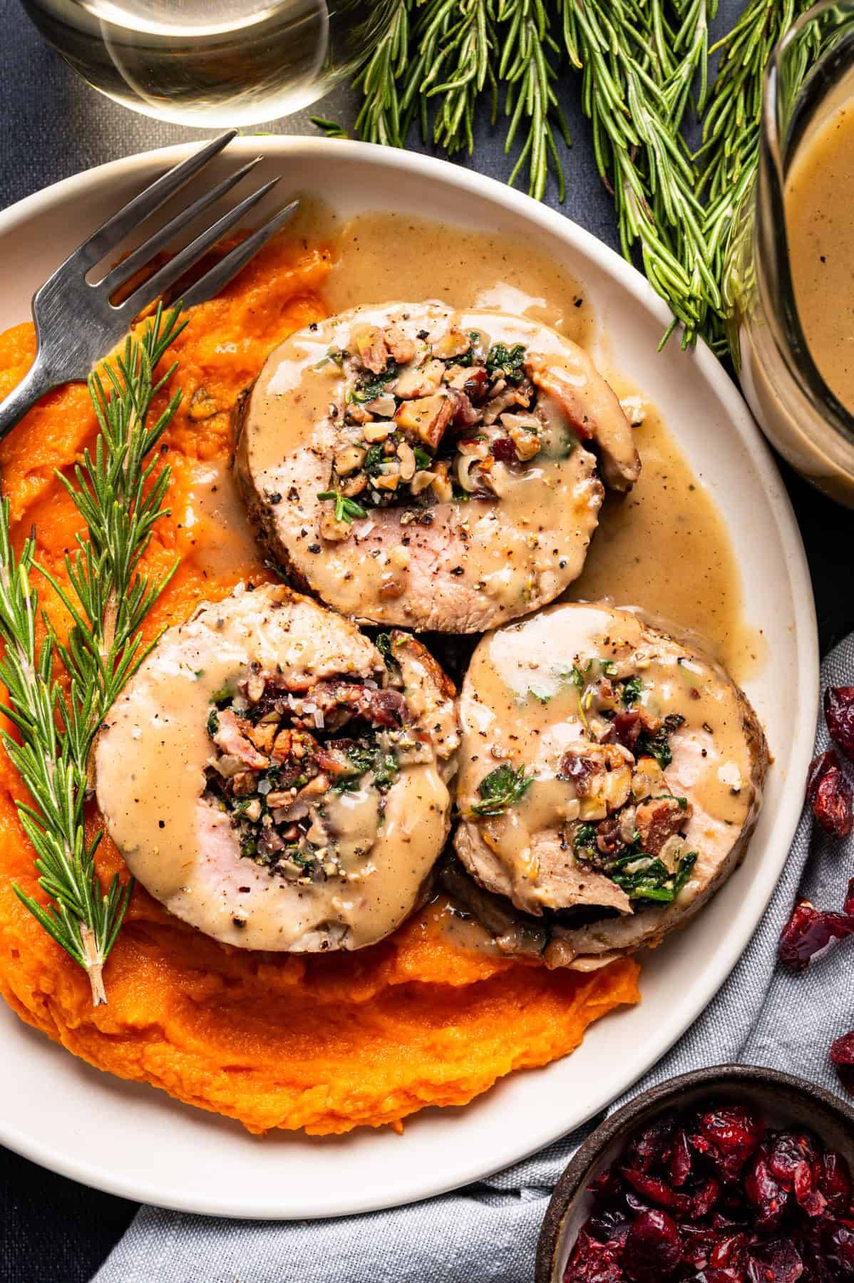 Stuffed Pork Tenderloin with Gravy and Mashed Sweet Potatoes - on a white plate.