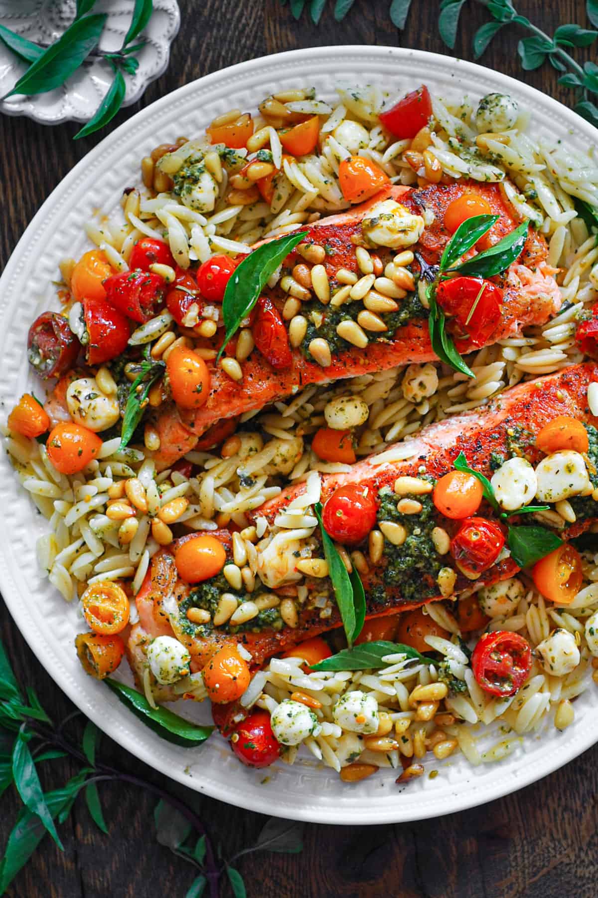 Spring Salmon Dinner with Basil Pesto, Orzo, Tomatoes, and Mozzarella - on a white plate.