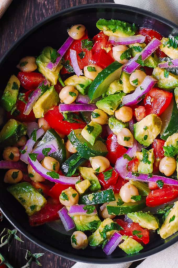 Chickpea Salad with Avocado, Tomato, Cucumber in a black bowl.