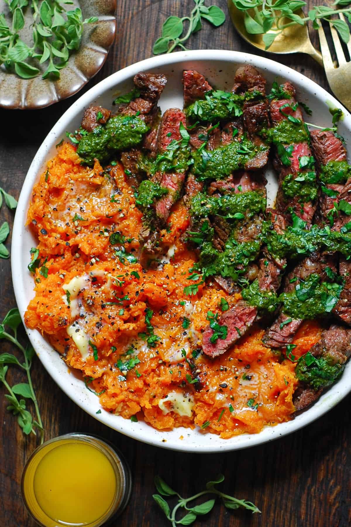 Flank Steak with Green Spinach Sauce and Buttered Mashed Sweet Potatoes on a white plate.