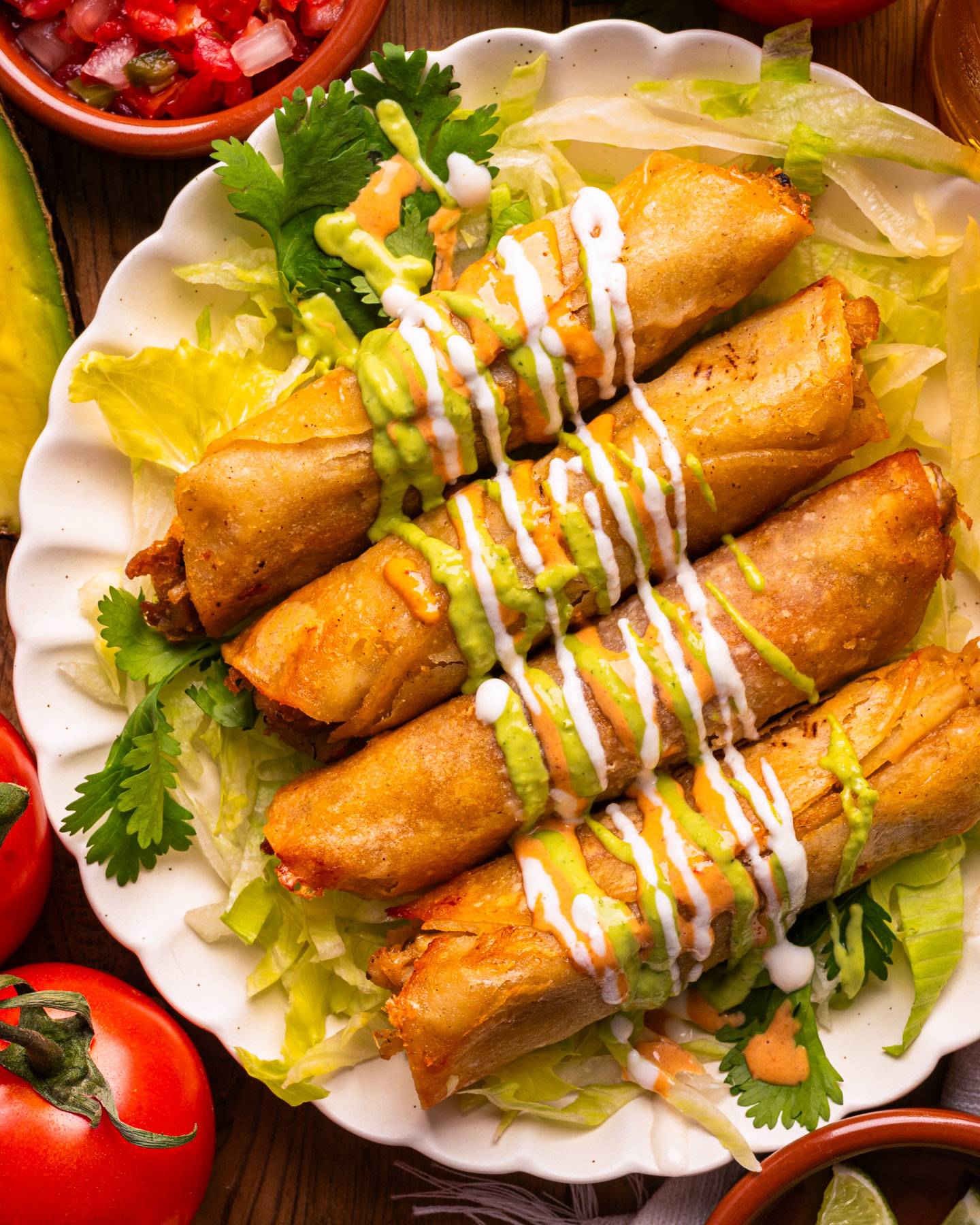 Crispy, Cheesy, Chicken Taquitos (Baked NOT Fried) with 3 Creamy Sauces: Garlic Crema, smoky Chipotle Aioli, and bright Avocado-Cilantro Lime Crema - on a white plate.