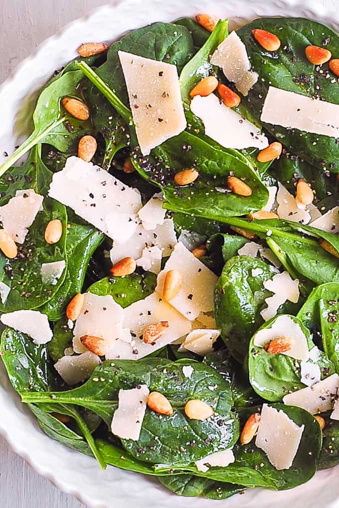 Simple Spinach Salad with Pine Nuts, Parmesan Cheese, and Lemon Dressing in a bowl.