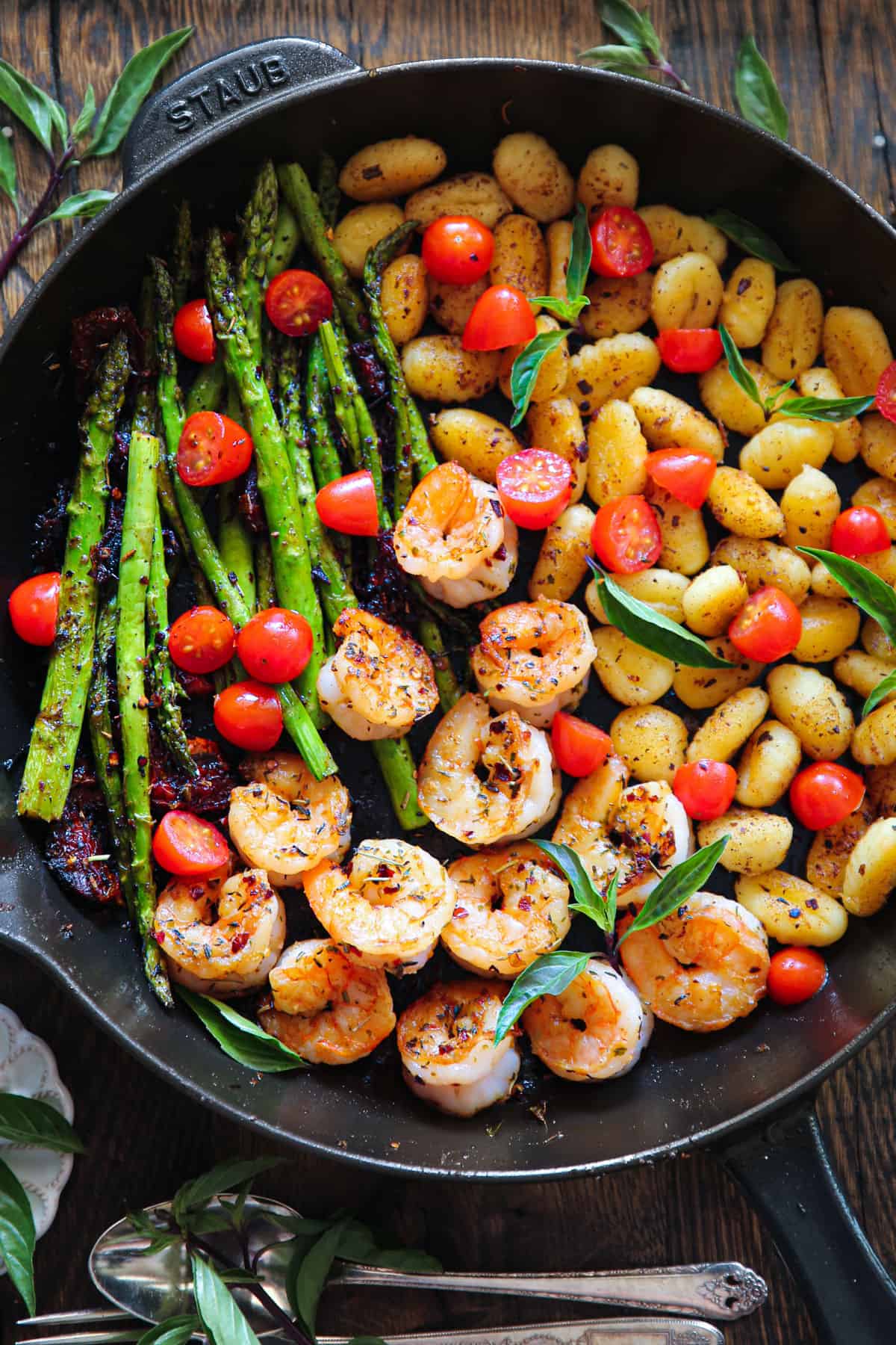 Shrimp Gnocchi and Veggies (cherry tomatoes, sun-dried tomatoes, and asparagus) in a cast iron pan.