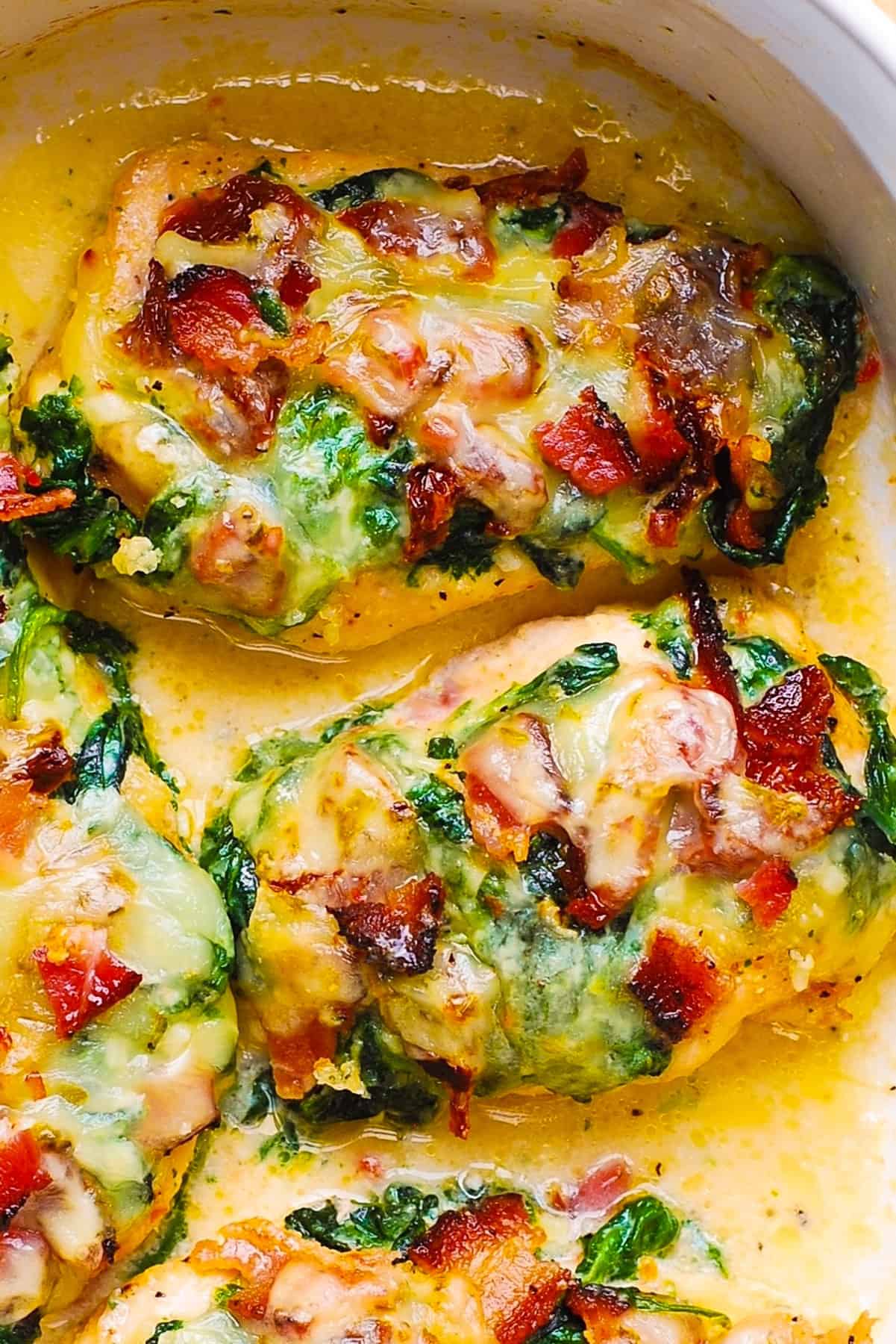Baked Chicken Breasts with Bacon, Creamed Spinach, and Sun-Dried Tomatoes in a white baking dish.