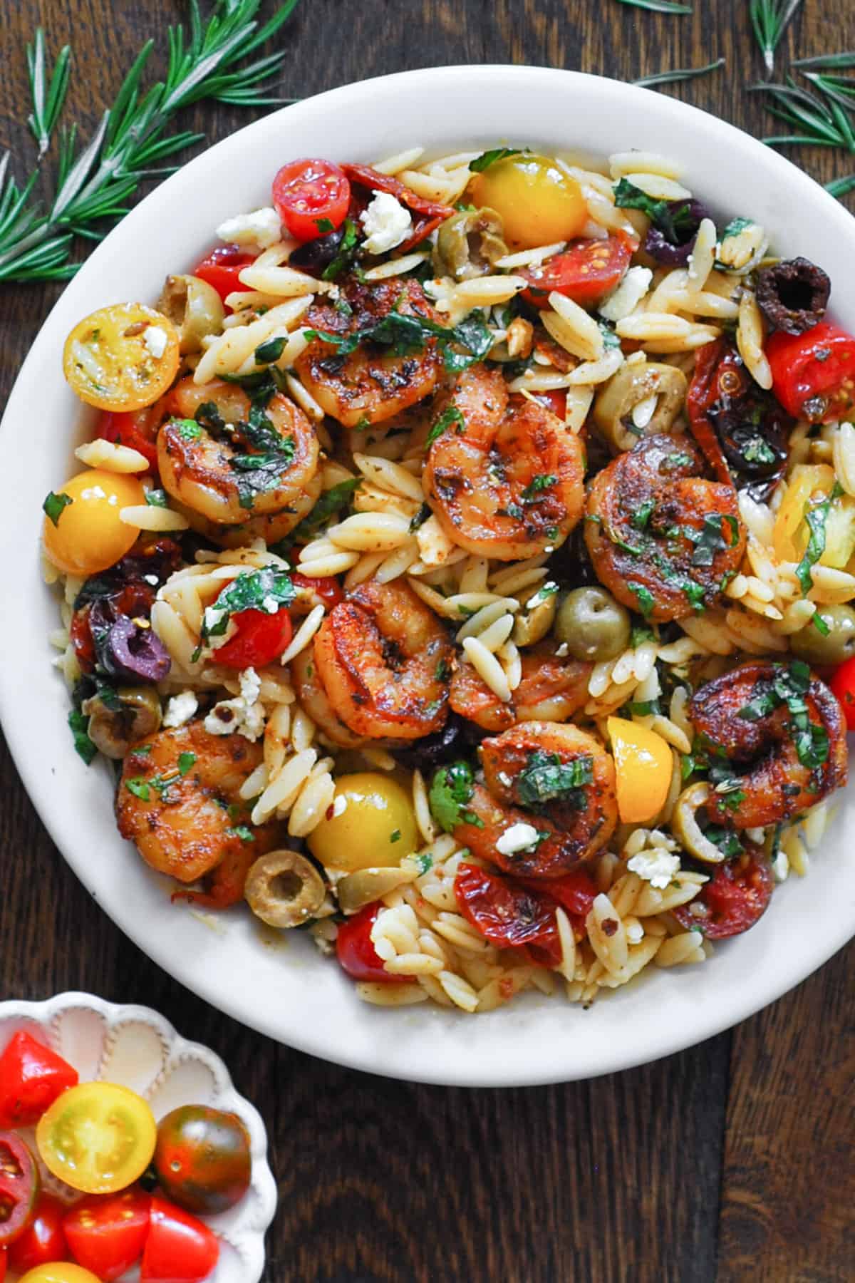 Greek Shrimp Orzo with Cherry Tomatoes, Sun-Dried Tomatoes, Feta, Green and Kalamata Olives on a white plate.