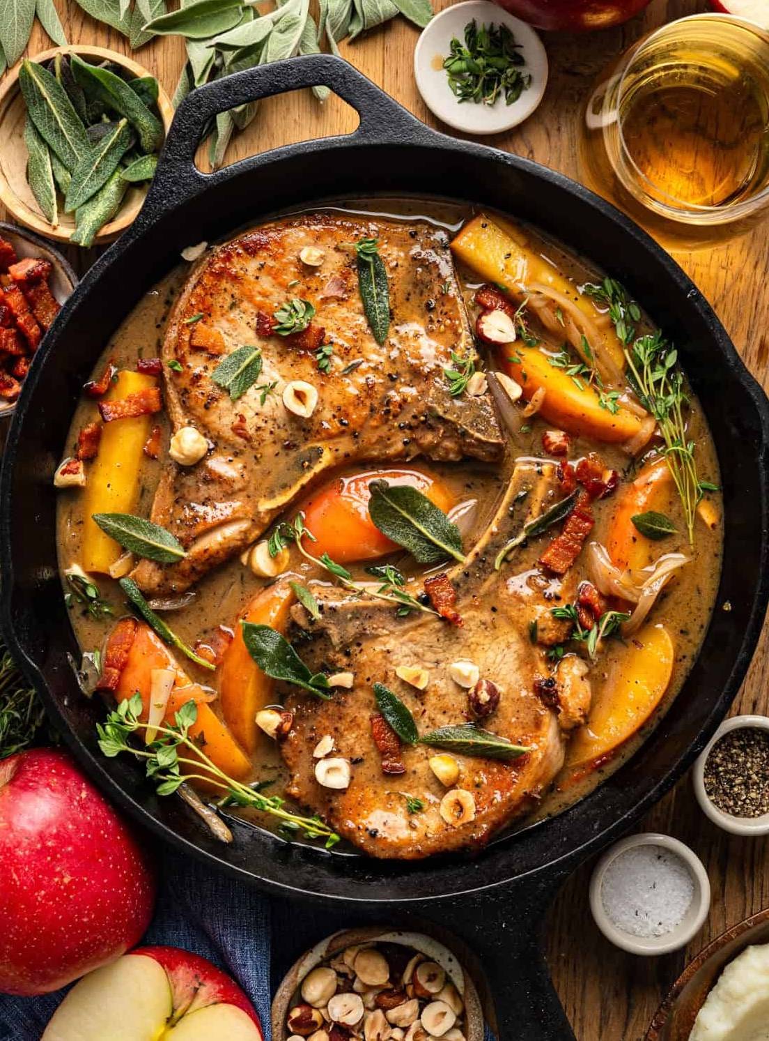 Pork Chops with Apples, Bacon, Nuts, and Apple Cider Dijon Sauce in a cast iron skillet. 