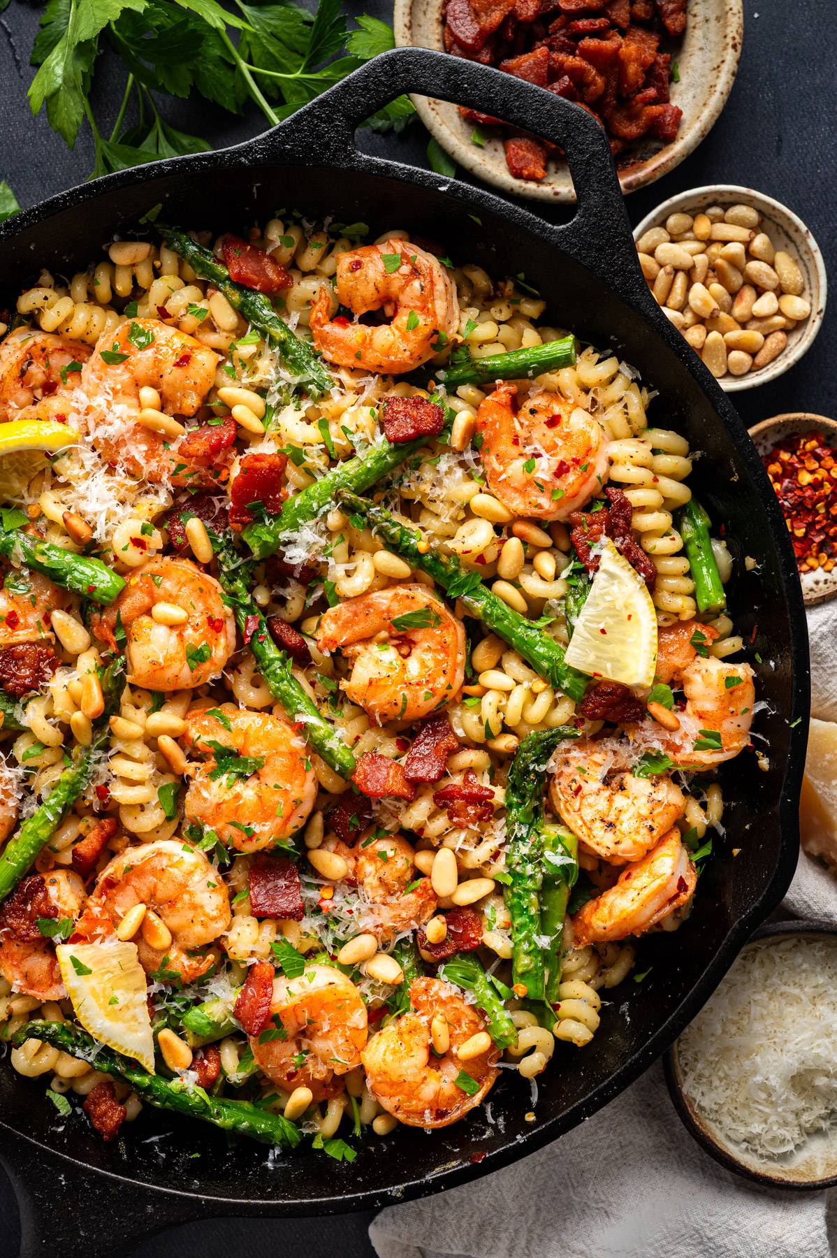 Shrimp Asparagus Pasta with Bacon, Pine Nuts, and Lemon-Butter Parmesan Sauce in a cast iron skillet.