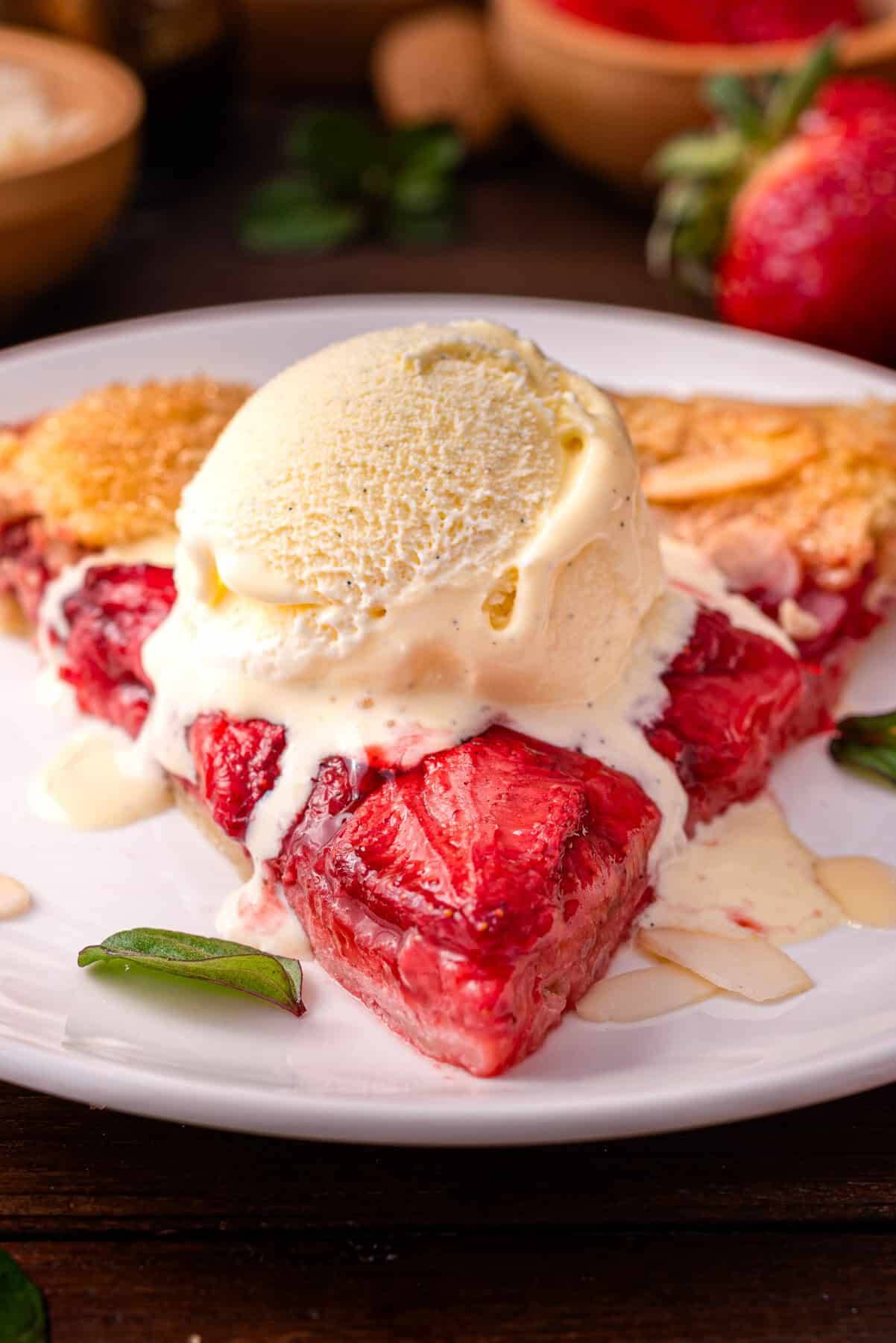 A slice of strawberry galette with ice cream on a plate.