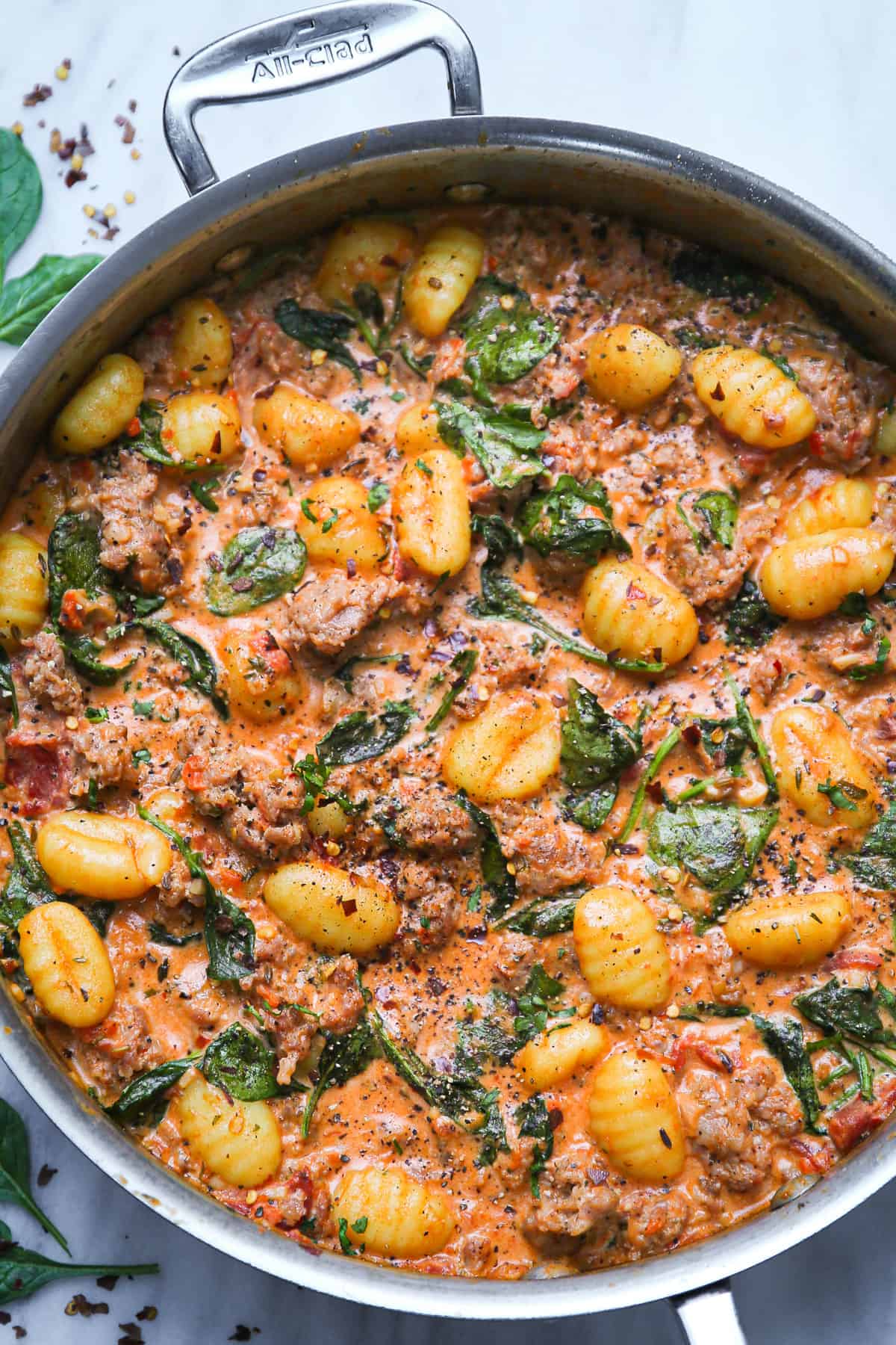 Creamy Sausage Gnocchi with Spinach and Tomato Sauce in a stainless steel pan.