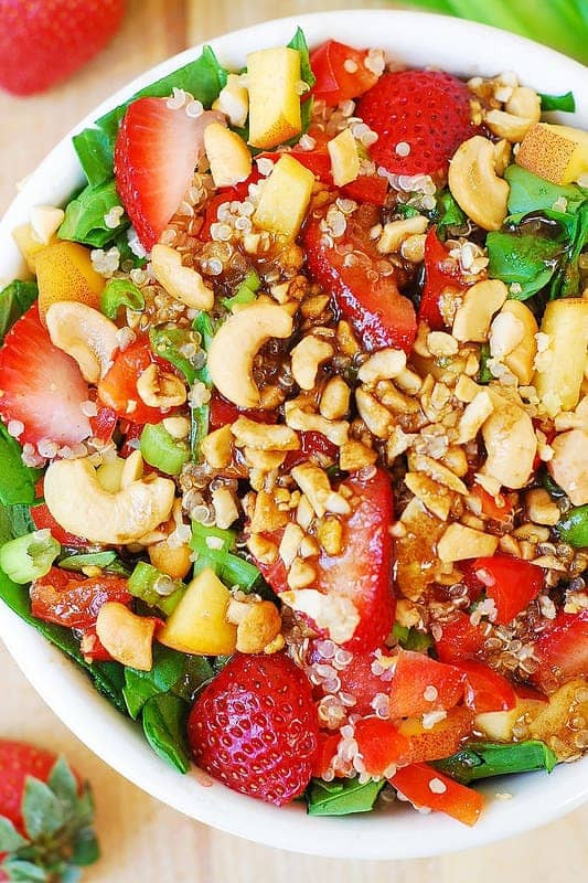 Strawberry, Quinoa, Spinach and Cashew Salad in a white bowl.