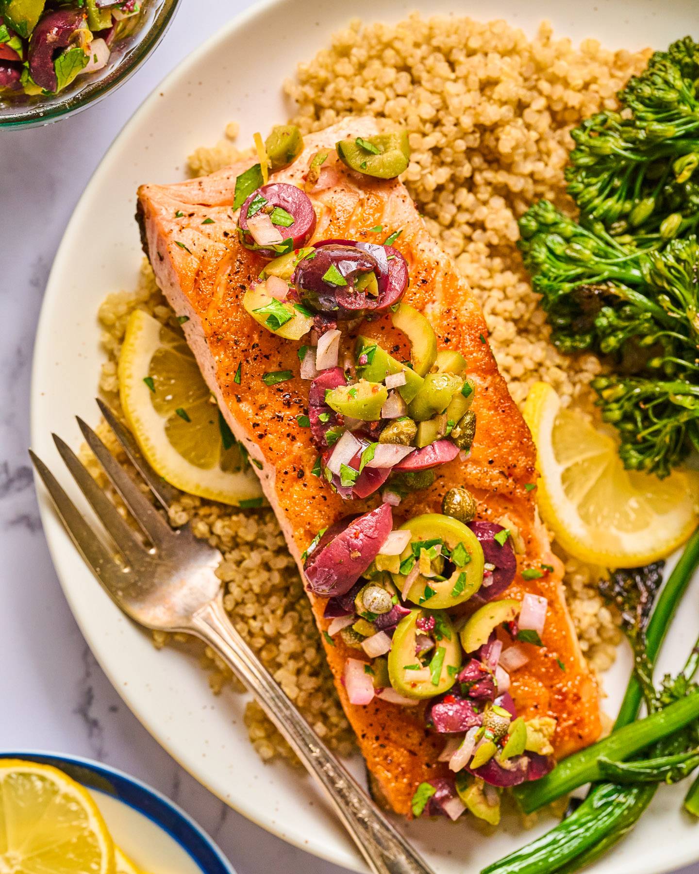 Salmon with Chunky Olive-Caper Sauce, Quinoa, and Broccoli Rabe on a plate.