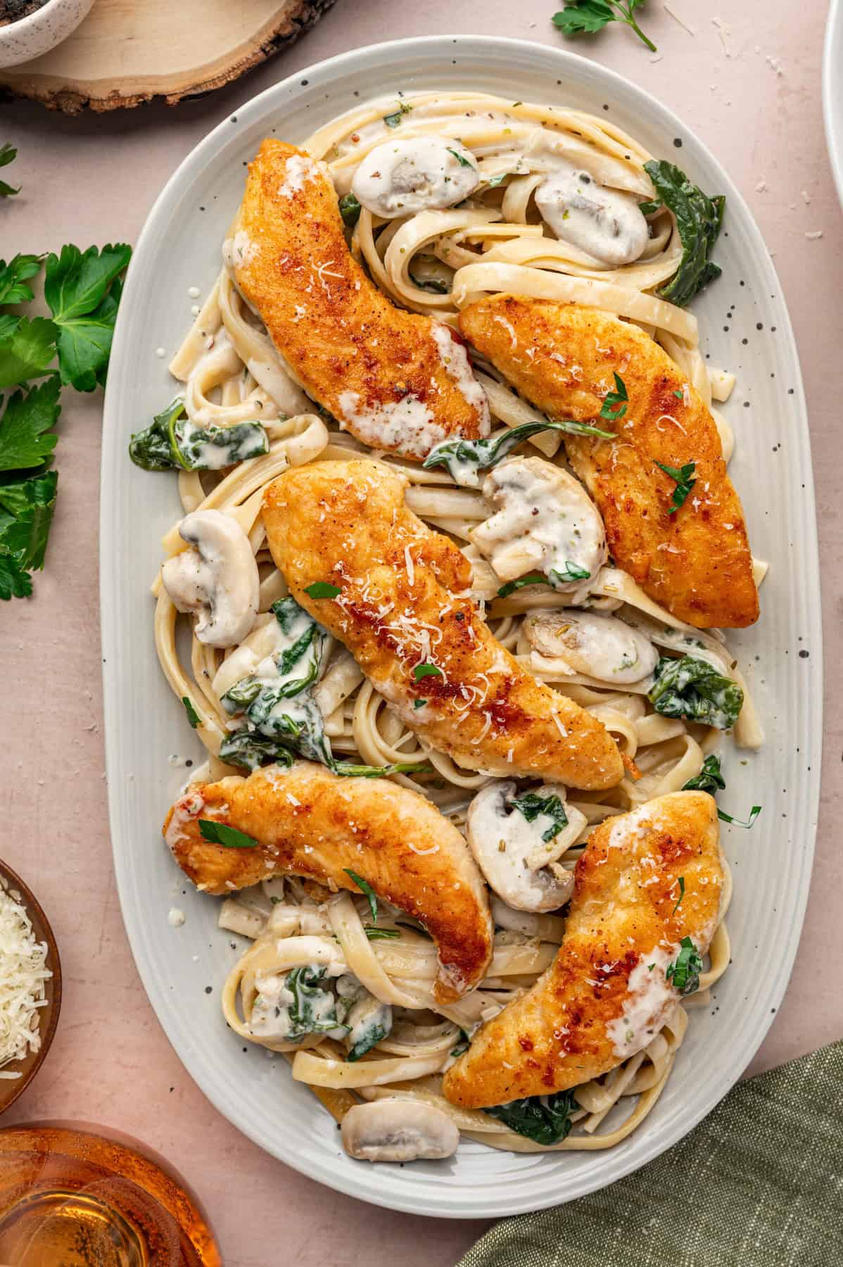 Chicken Marsala Fettuccine with Spinach and Mushrooms on an elongated white plate.