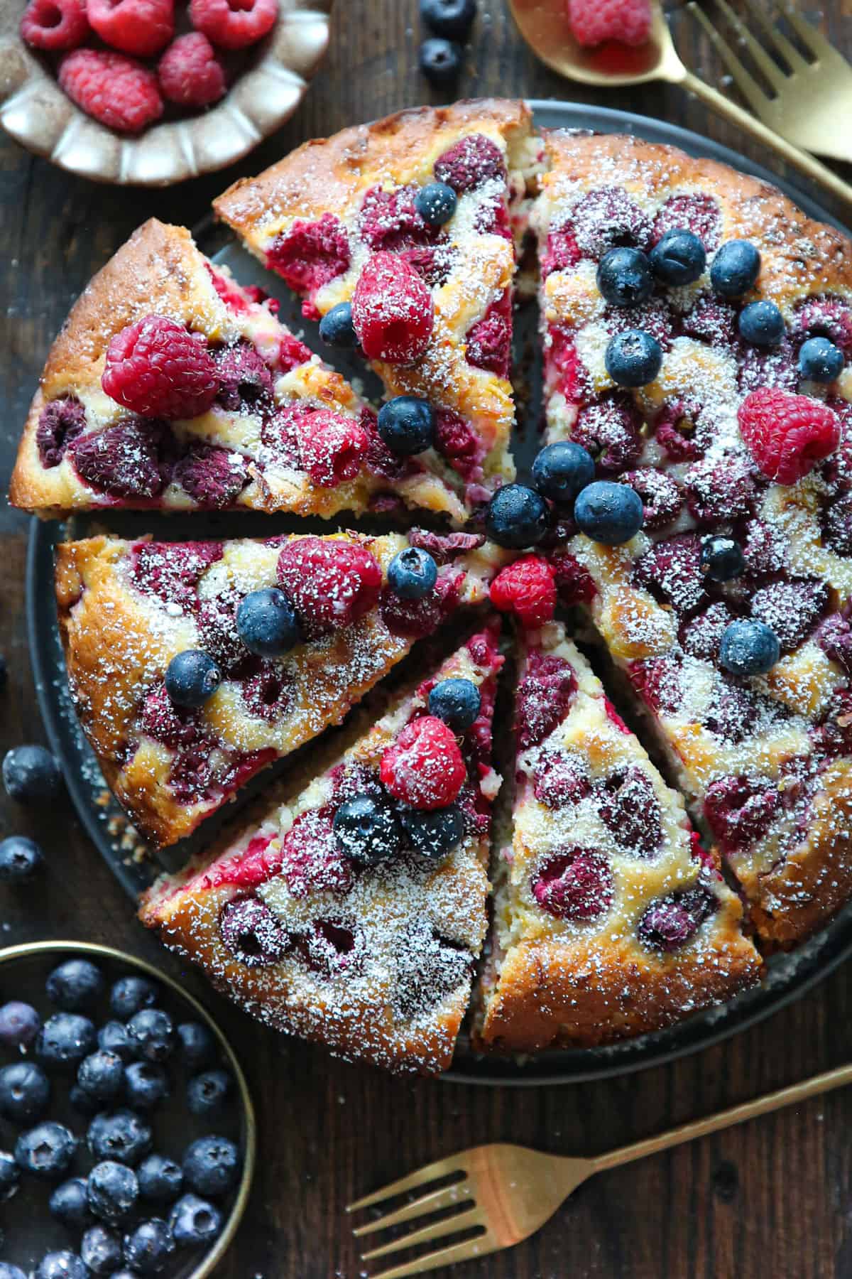 Raspberry and blueberry lemon cake on a dark background.