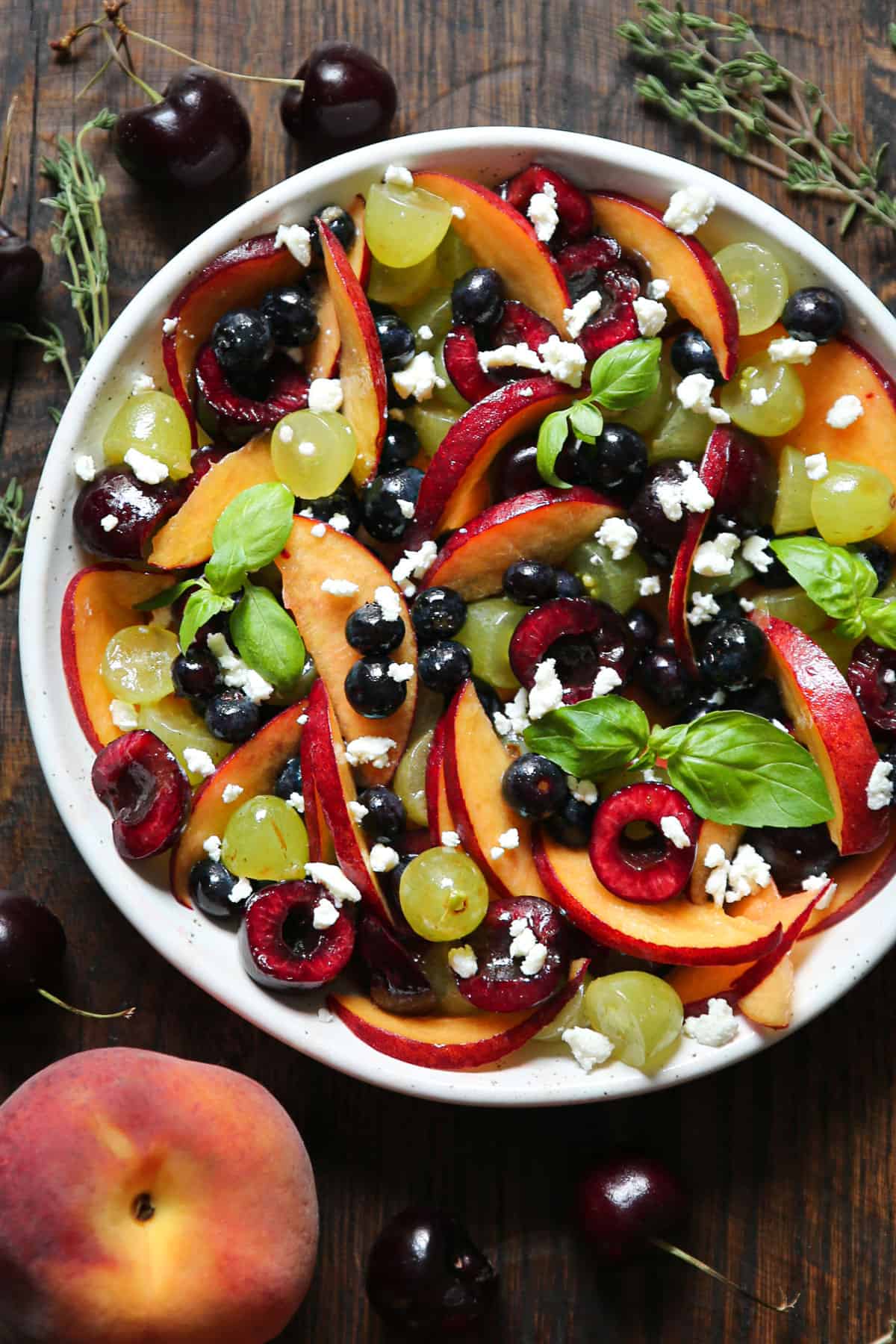 Summer Fruit Salad with Honey-Lemon Dressing (yellow peaches, red sweet cherries, blueberries, grapes, feta cheese) in a bowl.