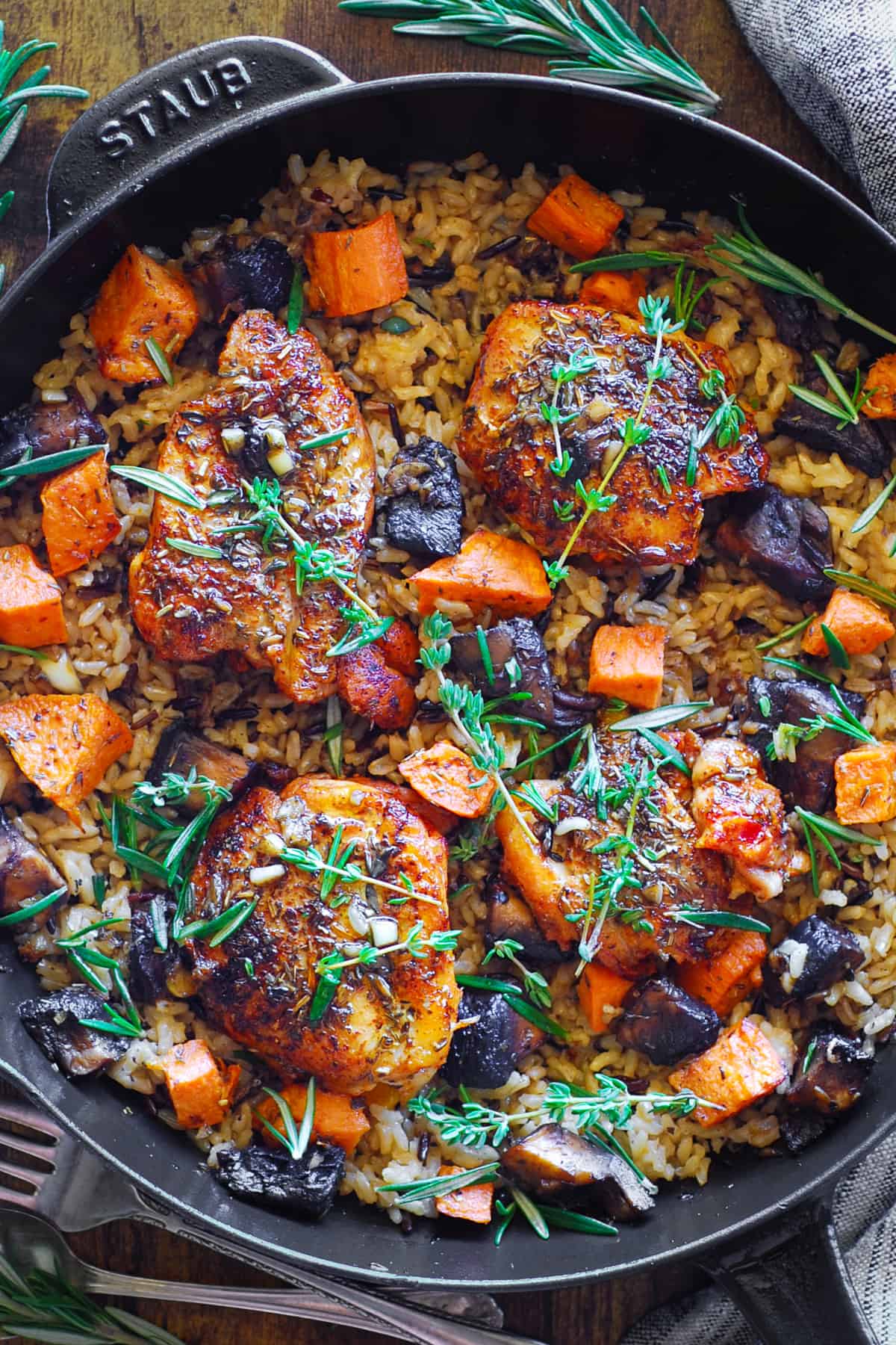Chicken Thighs and Wild Rice with Roasted Sweet Potatoes and Mushrooms in a cast iron skillet.