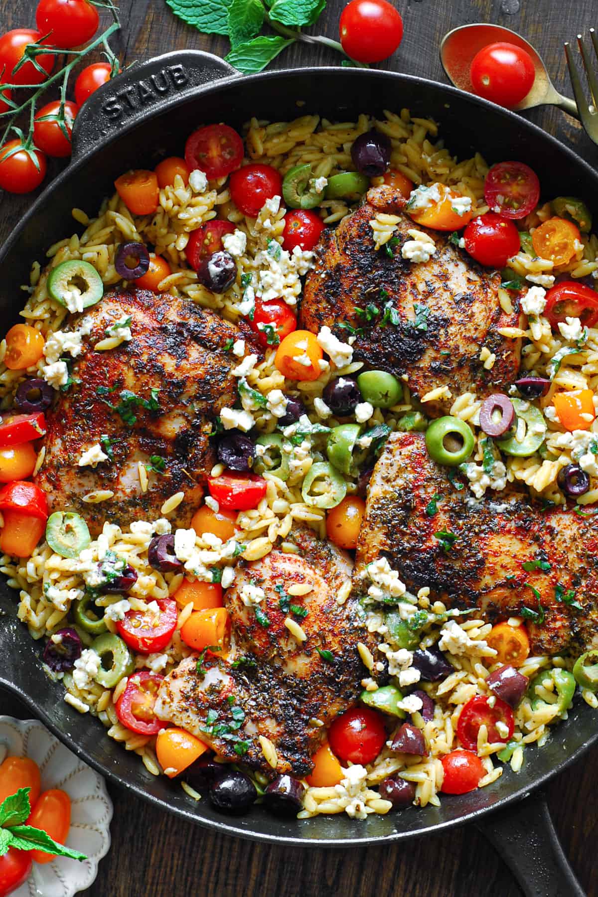 Greek Chicken Orzo with Cherry Tomatoes, Olives - in a cast iron skillet.