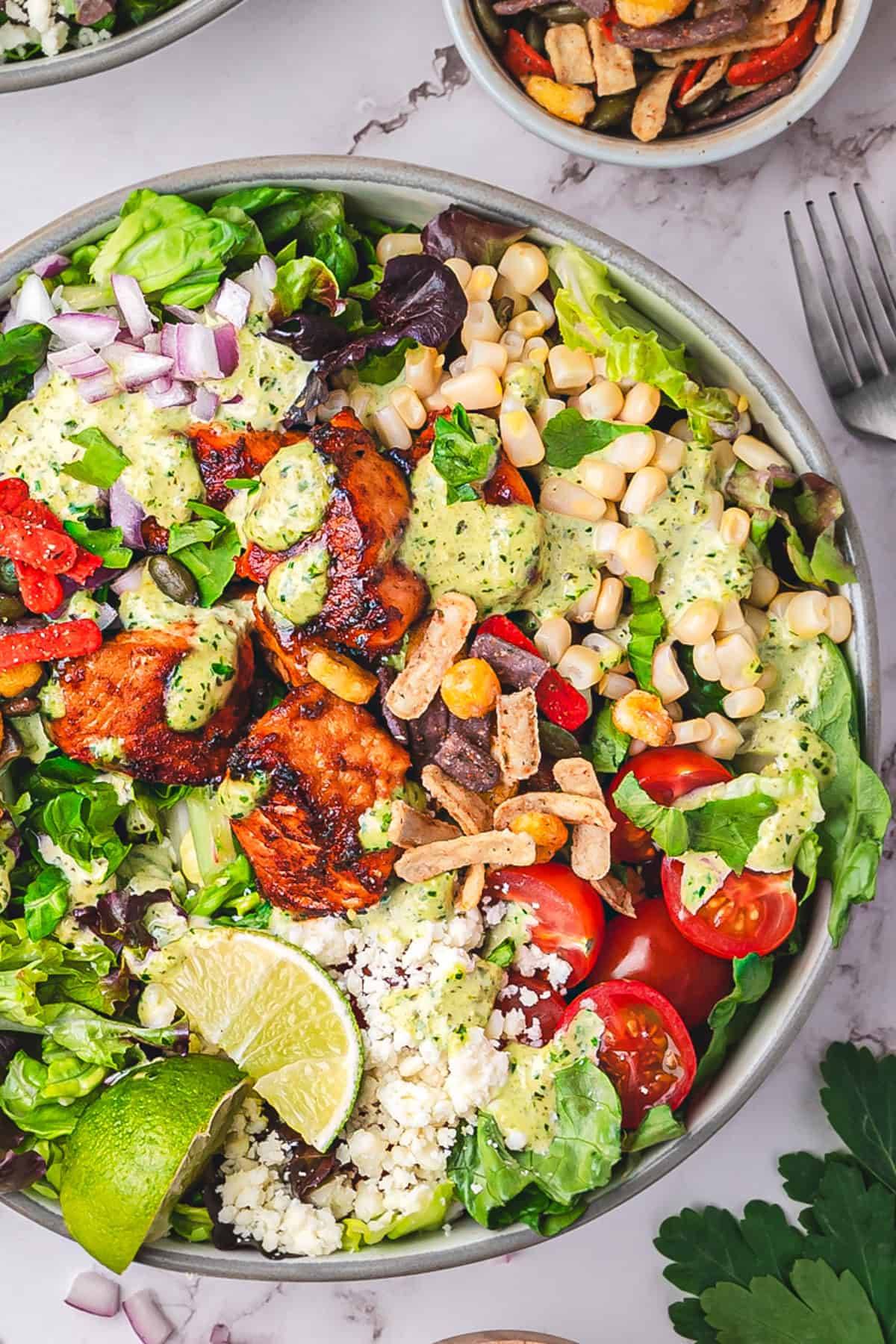 Mexican Salmon Salad Bowl with Lettuce, Corn, Tomatoes, Cotija, and easy homemade Roasted Poblano Ranch Dressing - in a bowl.