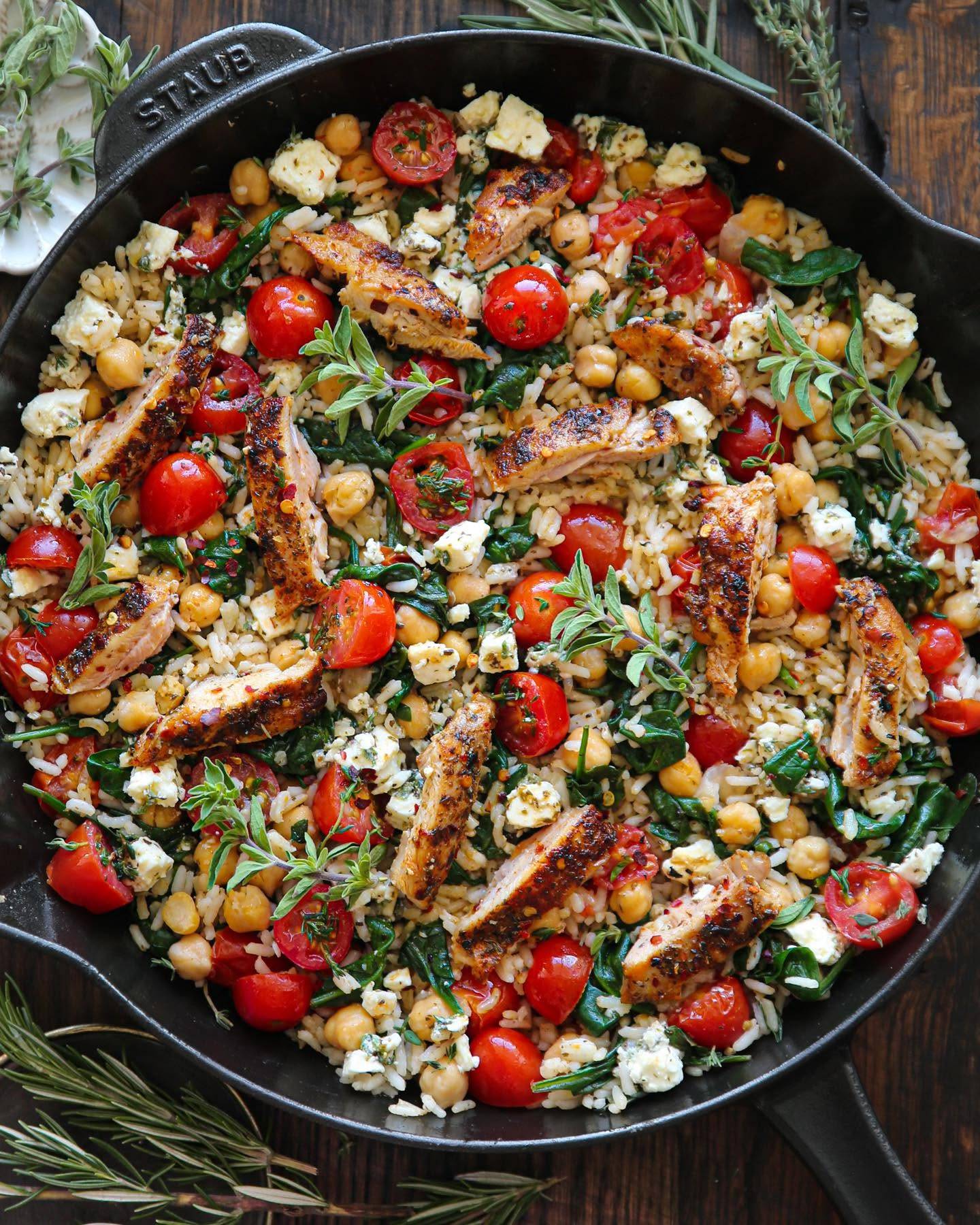 Greek Chicken and Lemon Rice with Chickpeas, Cherry Tomatoes, and Spinach in a cast iron skillet.