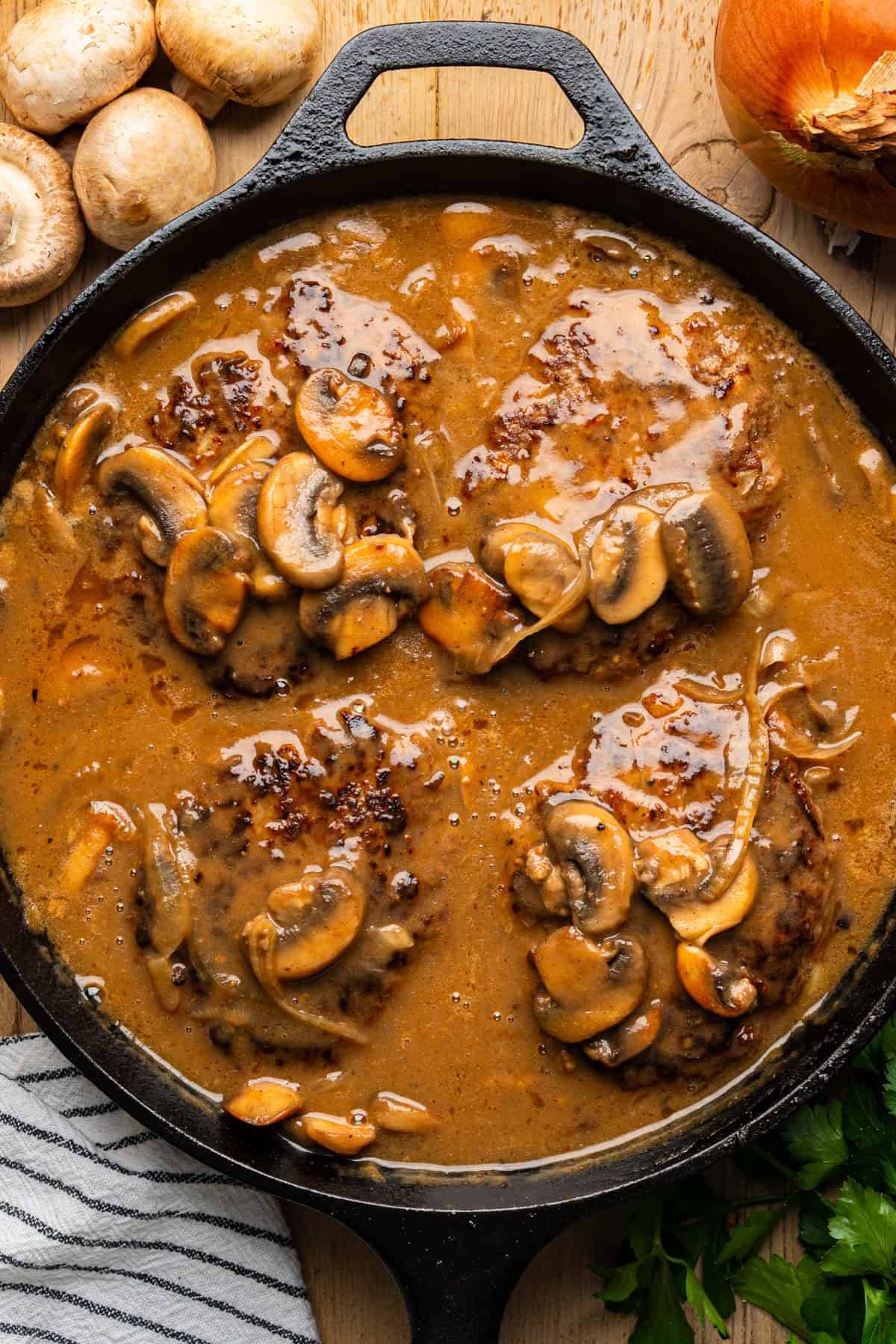 Salisbury Steak (Ground Beef Patties) with Mushroom Gravy in a cast iron skillet.