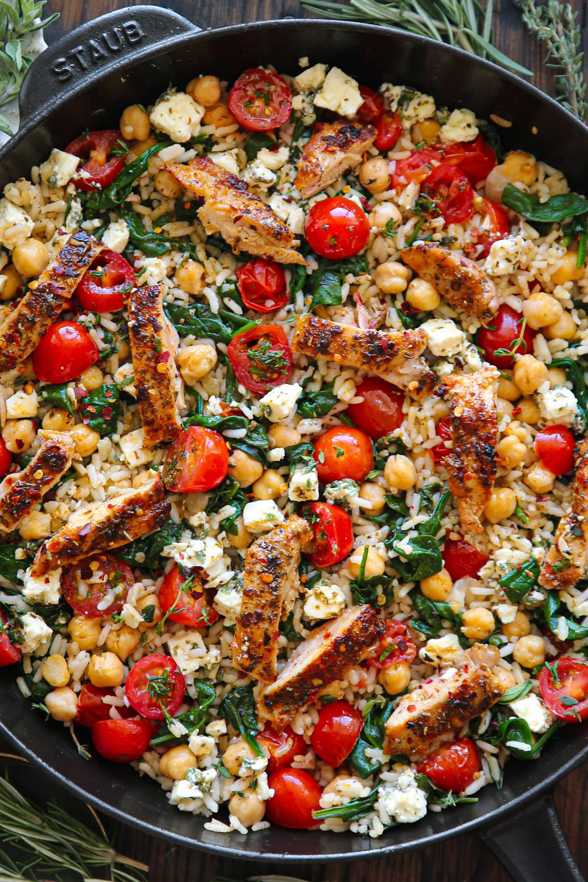 Greek Chicken and Lemon Rice​ with chickpeas, cherry tomatoes, and spinach - in a cast iron skillet.