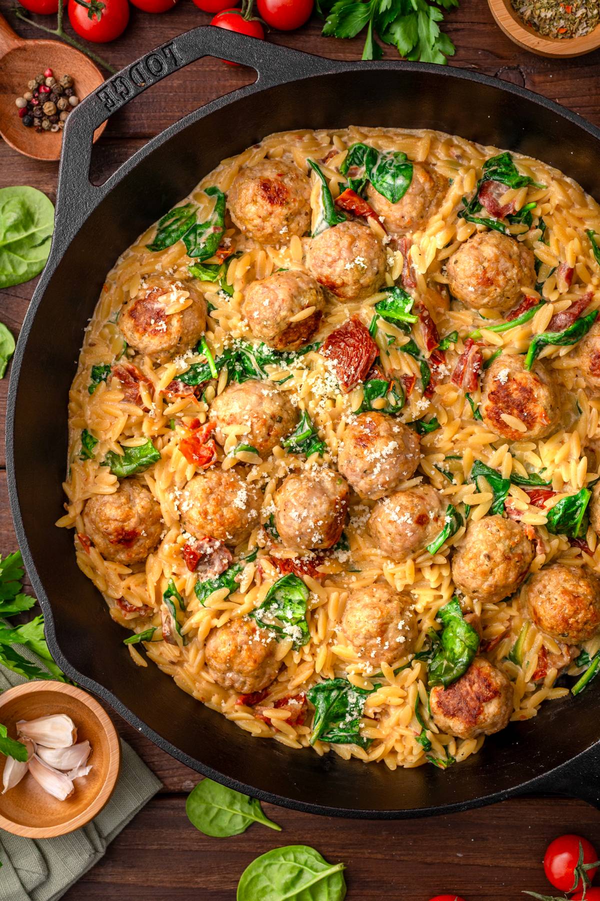Baked Chicken Meatballs with Orzo (with creamy sun-dried tomato and spinach sauce) - in a cast iron skillet.