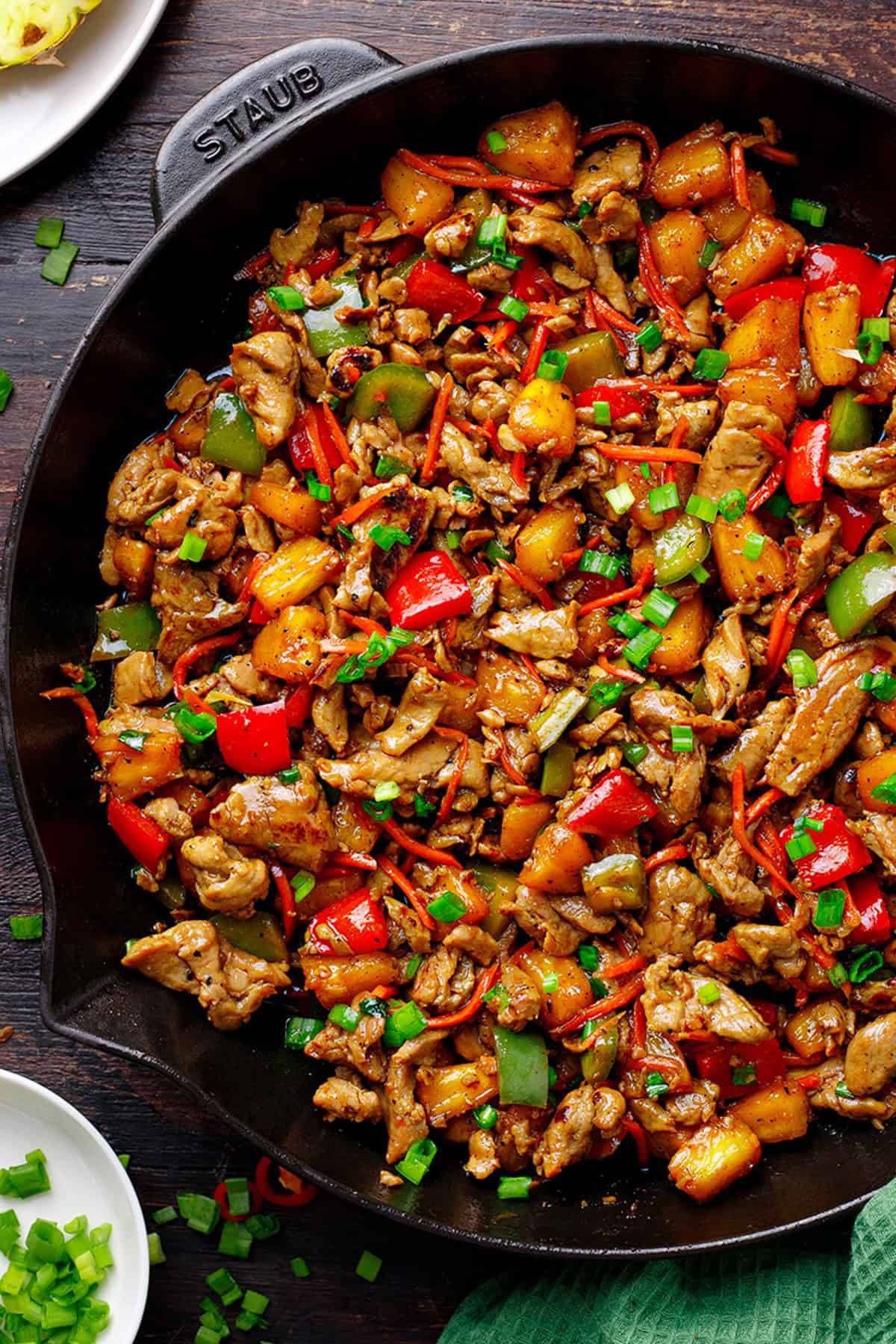 Pineapple Pork Stir-Fry (with juicy pineapple, colorful bell peppers, and carrots) in a cast iron skillet.