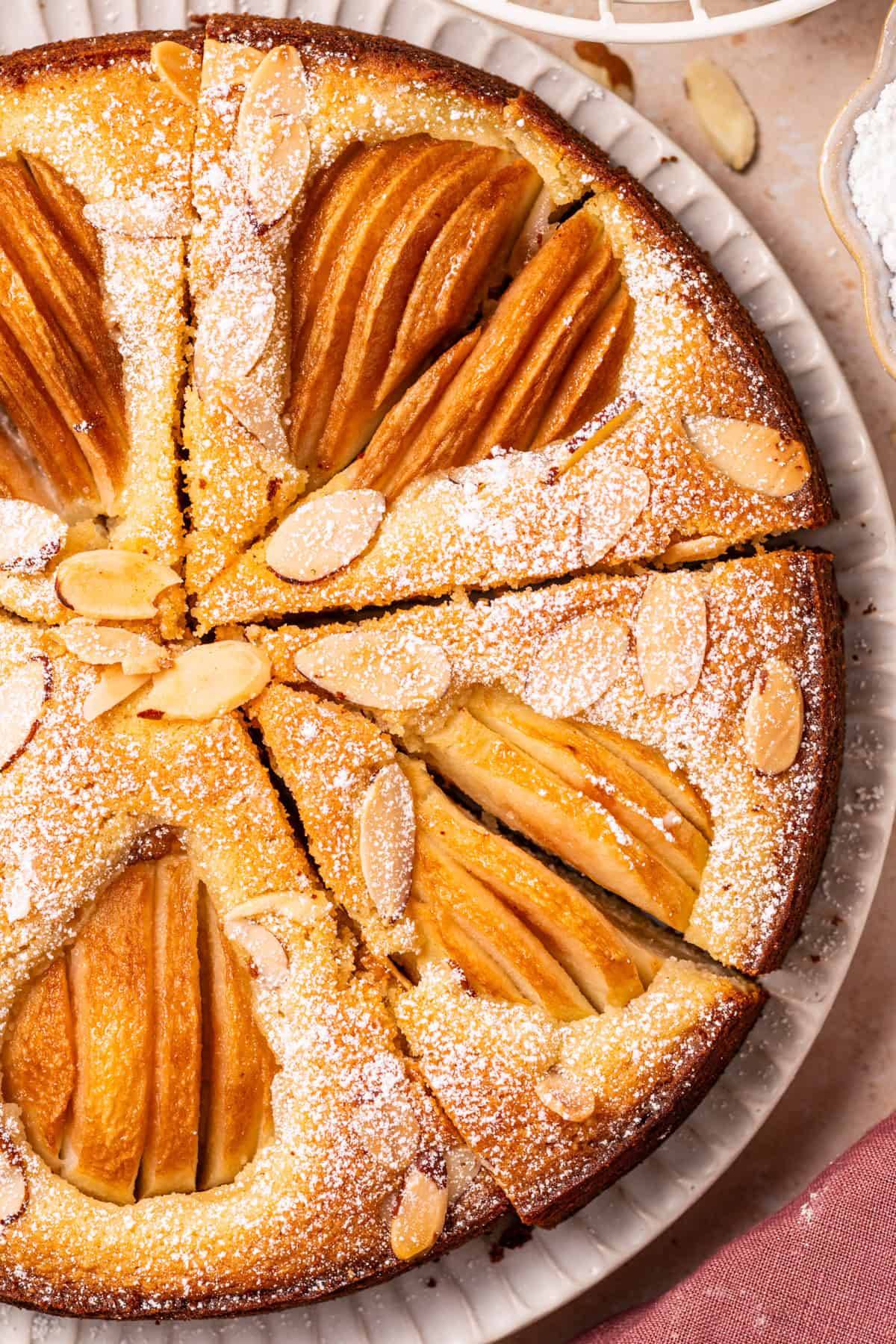 Pear Almond Cake dusted with powdered sugar on a white plate.