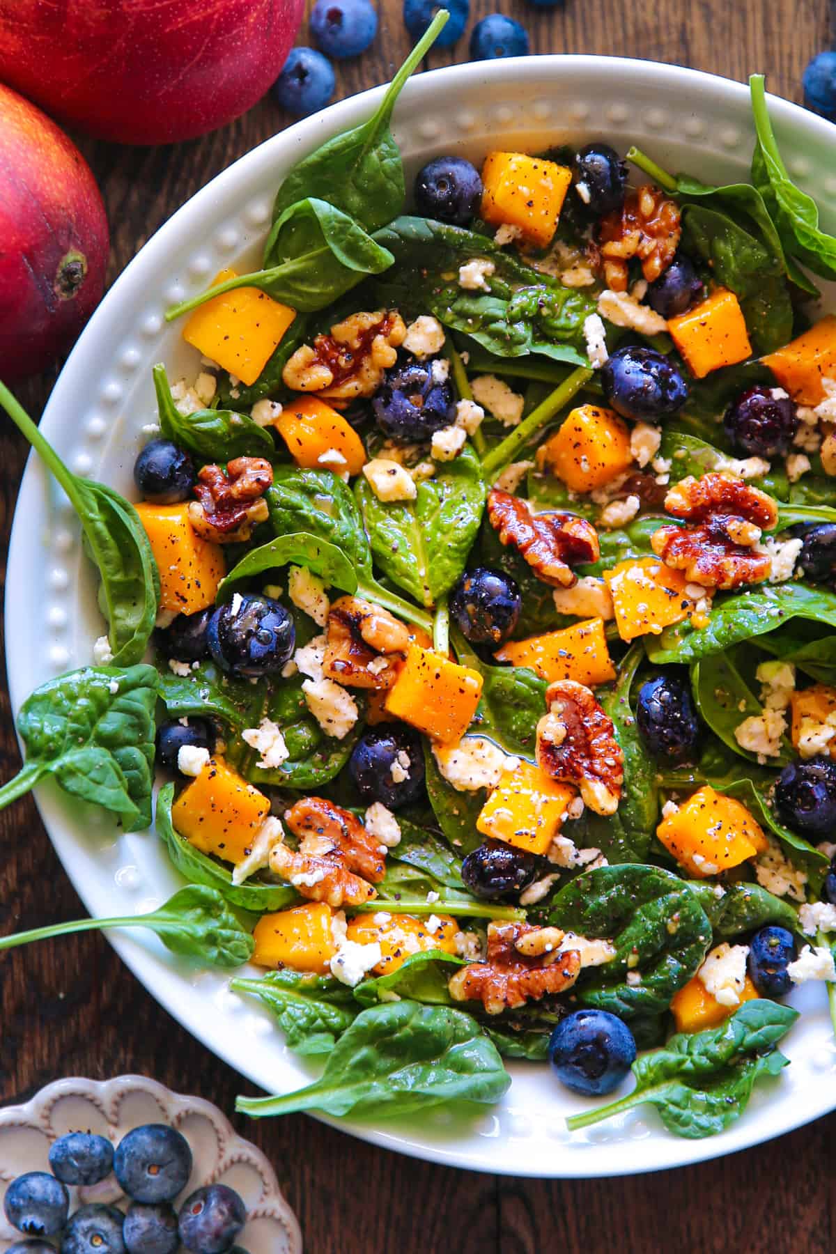 Mango Spinach Salad with Blueberries, Walnuts, and Feta Cheese in a bowl.