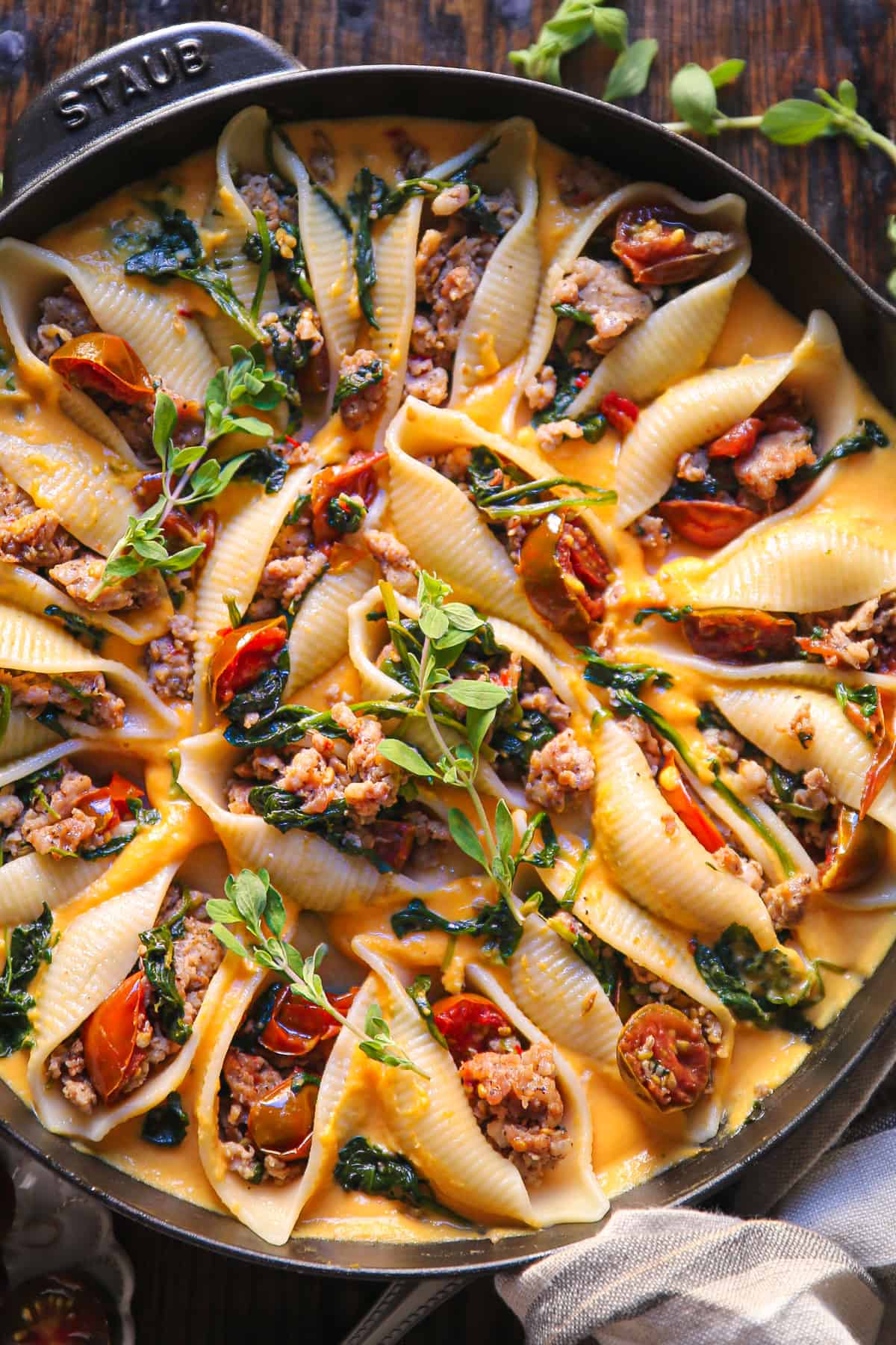 Creamy Butternut Squash Stuffed Pasta Shells with Sausage, Spinach, and Tomatoes in a cast iron skillet.