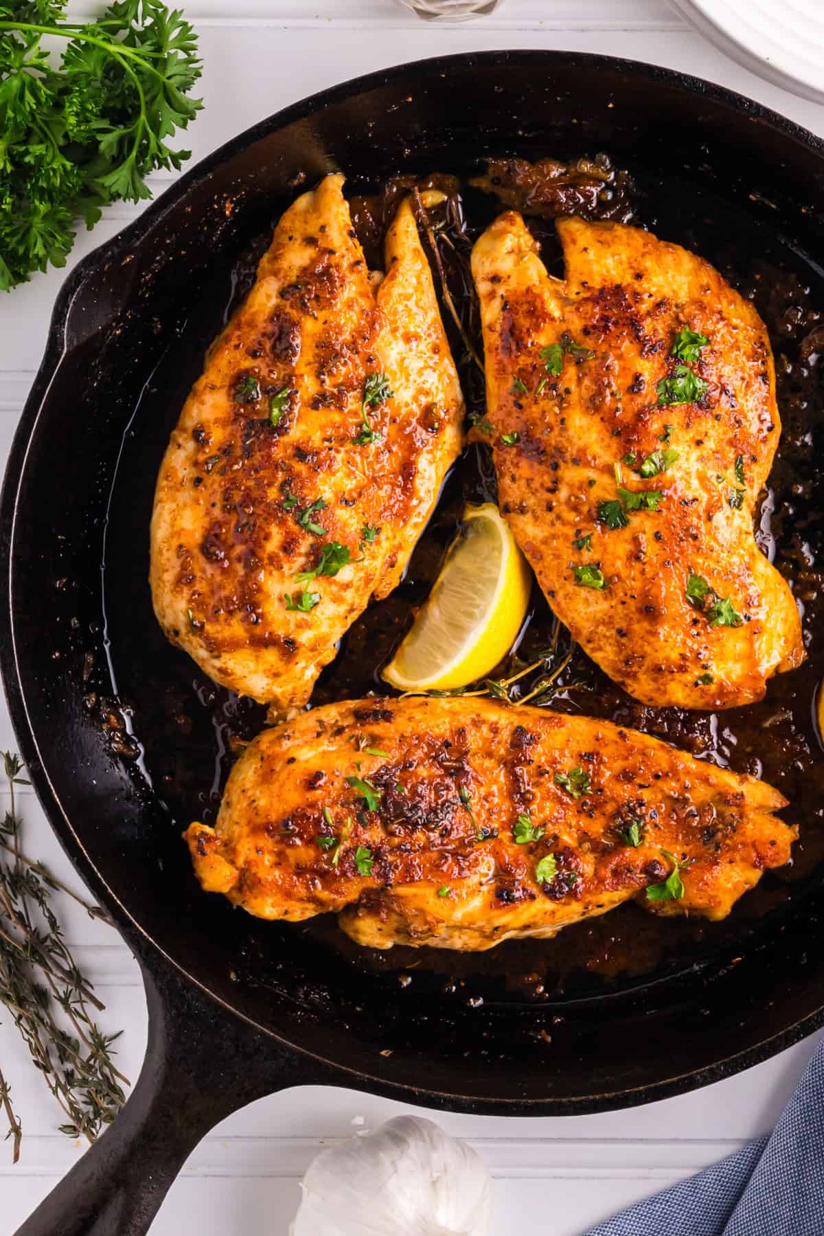 Pan-Seared Chicken Breasts​ with Garlic-Lemon Thyme Pan Sauce in a cast iron skillet.