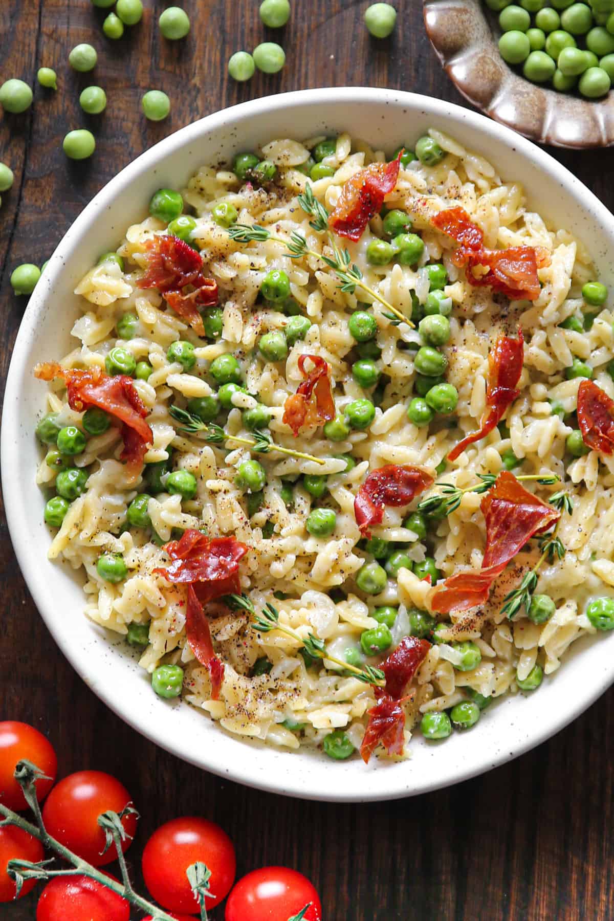 Creamy Garlic Parmesan Orzo with Green Peas and Crispy Prosciutto in a white bowl.