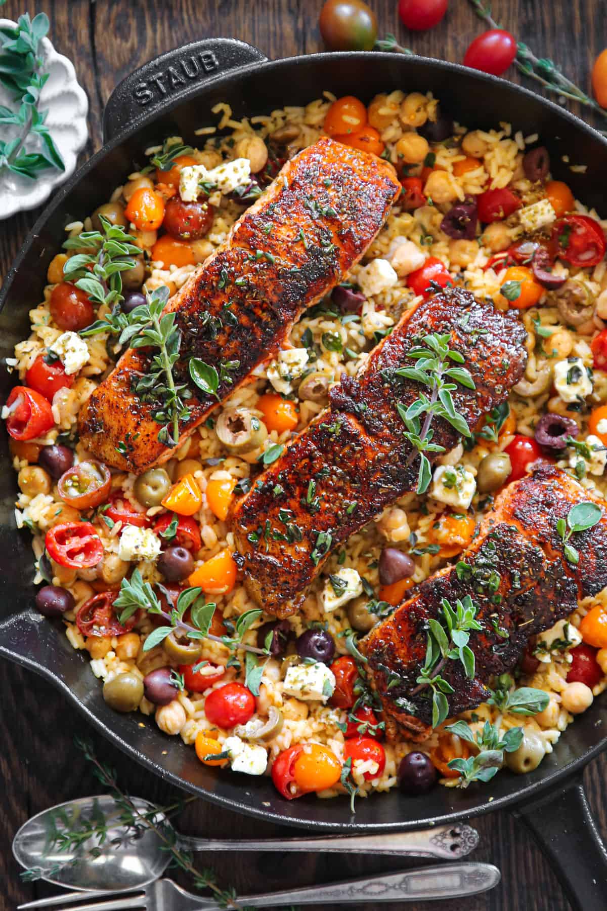 Mediterranean Salmon with rice, chickpeas, tomatoes, olives, and feta cheese - in a cast iron skillet.