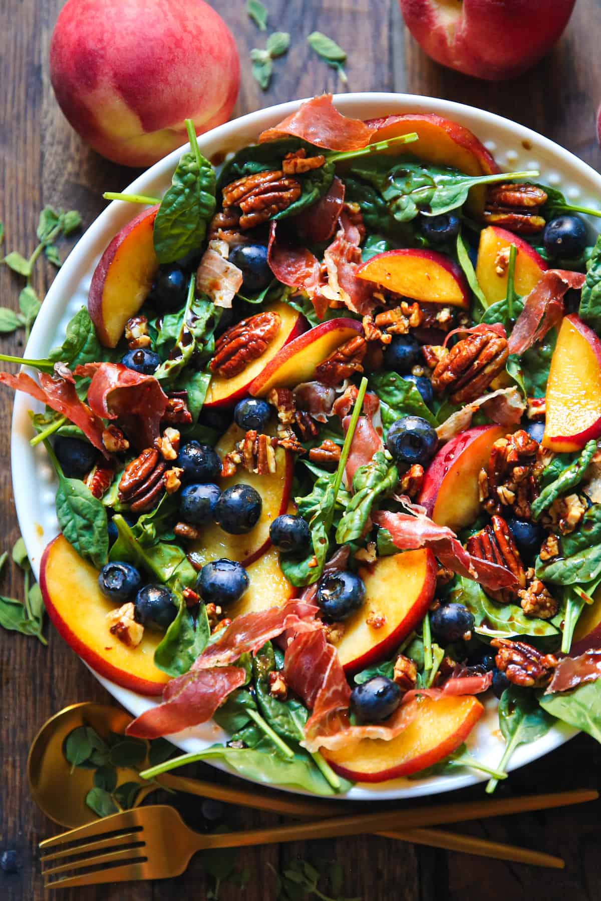 Peach & Blueberry Spinach Salad with Prosciutto, Pecans, and Balsamic Dressing - in a white bowl.