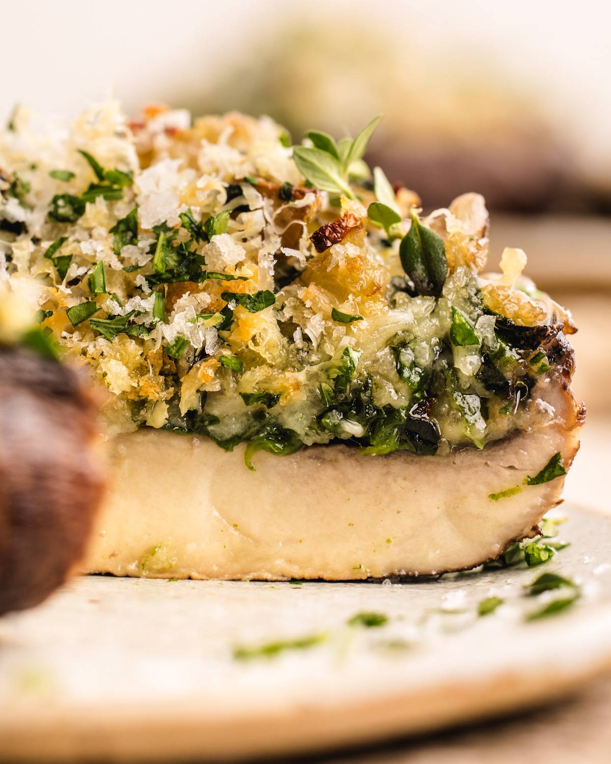 Baked Stuffed Portobello Mushrooms (with a savory filling of spinach, garlic, Gruyère, Parmesan, and breadcrumbs) - sliced on a plate.