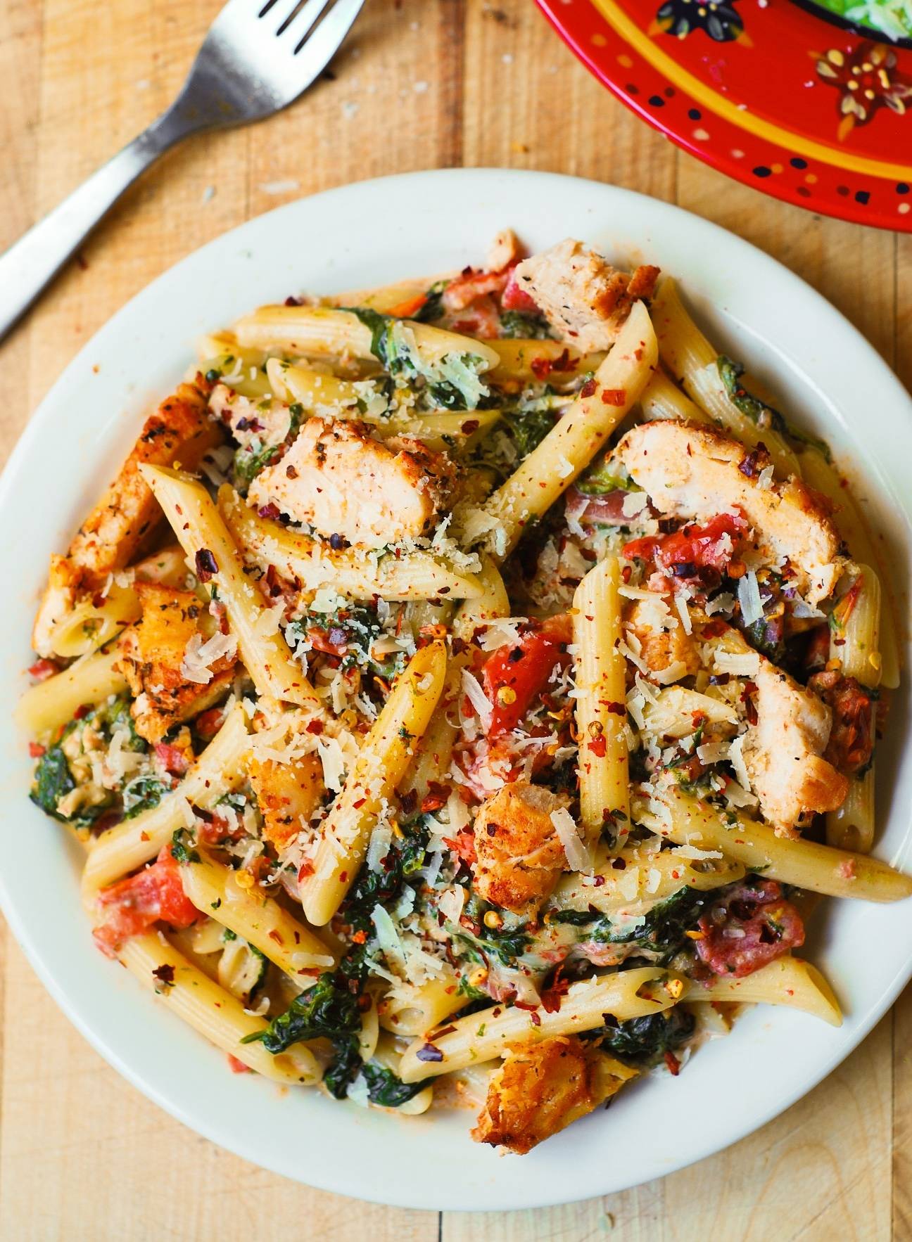 Creamy Chicken and Bacon Pasta with Spinach and Tomatoes in Garlic Cream Sauce on a plate.