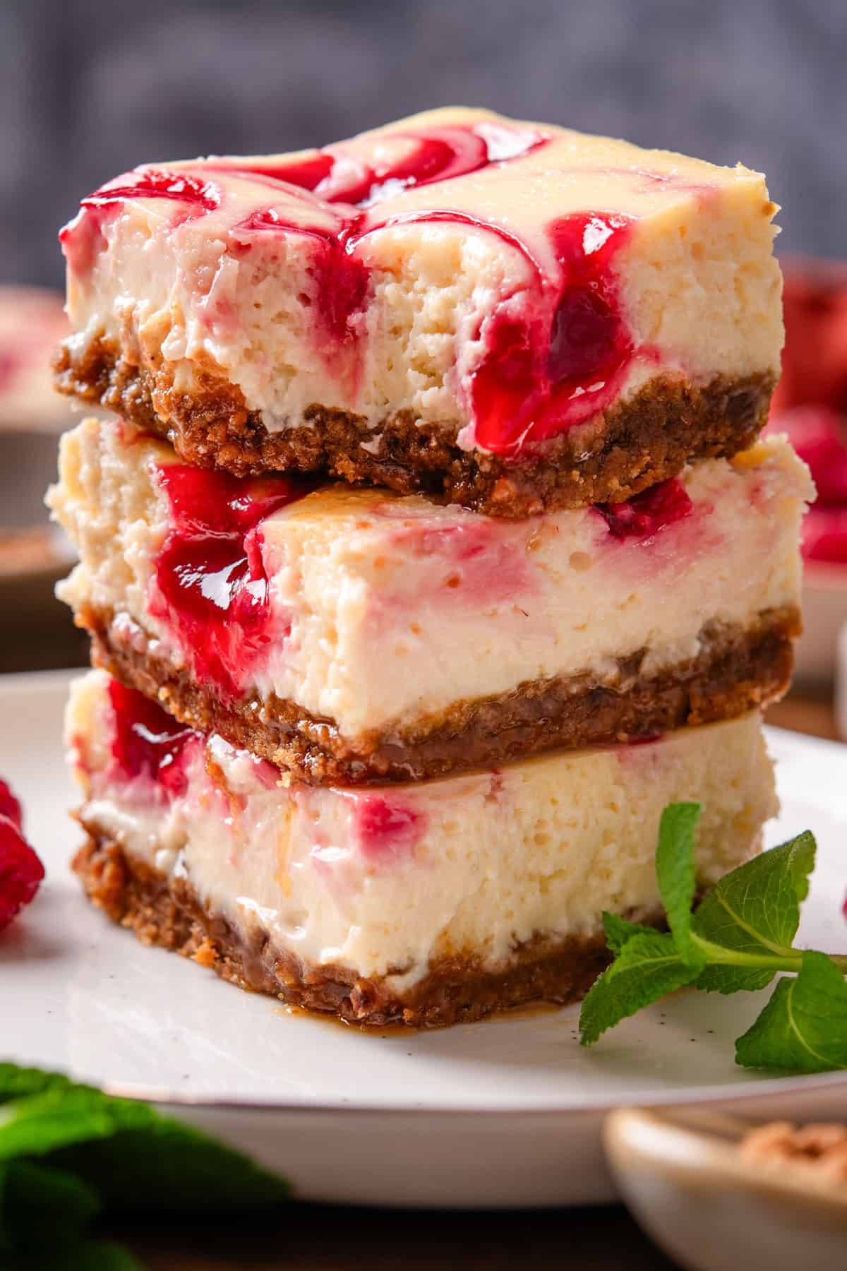 Lemon Raspberry Cheesecake Bars stacked on a plate.