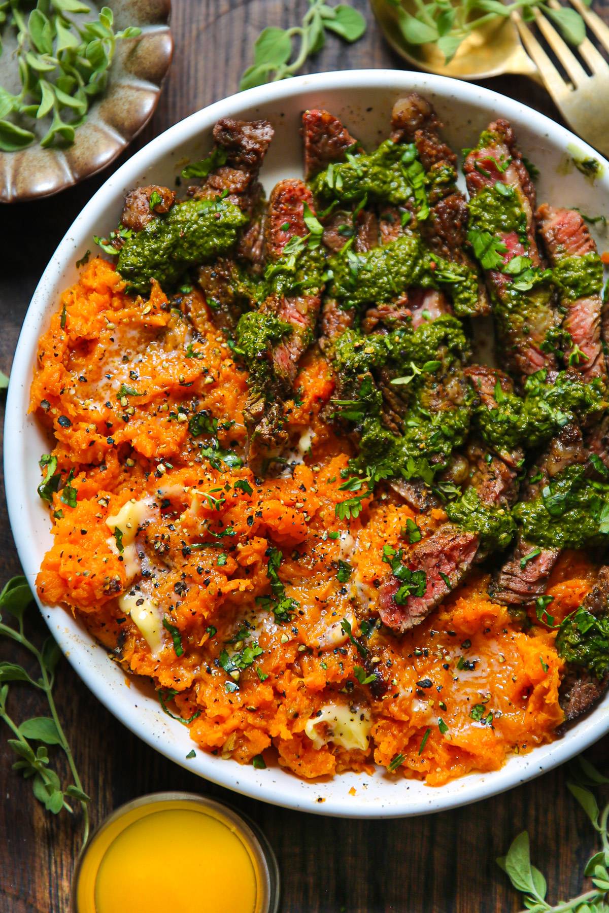 Flank Steak with Sweet Potatoes and Green Sauce (Spinach Pesto) on a white plate.