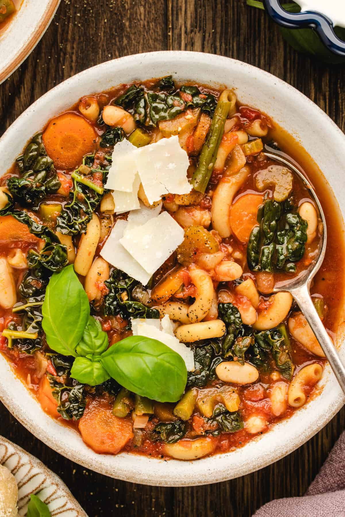 Minestrone Pasta Soup (with cannellini beans, kale, basil, tomatoes, carrots) in a white bowl.