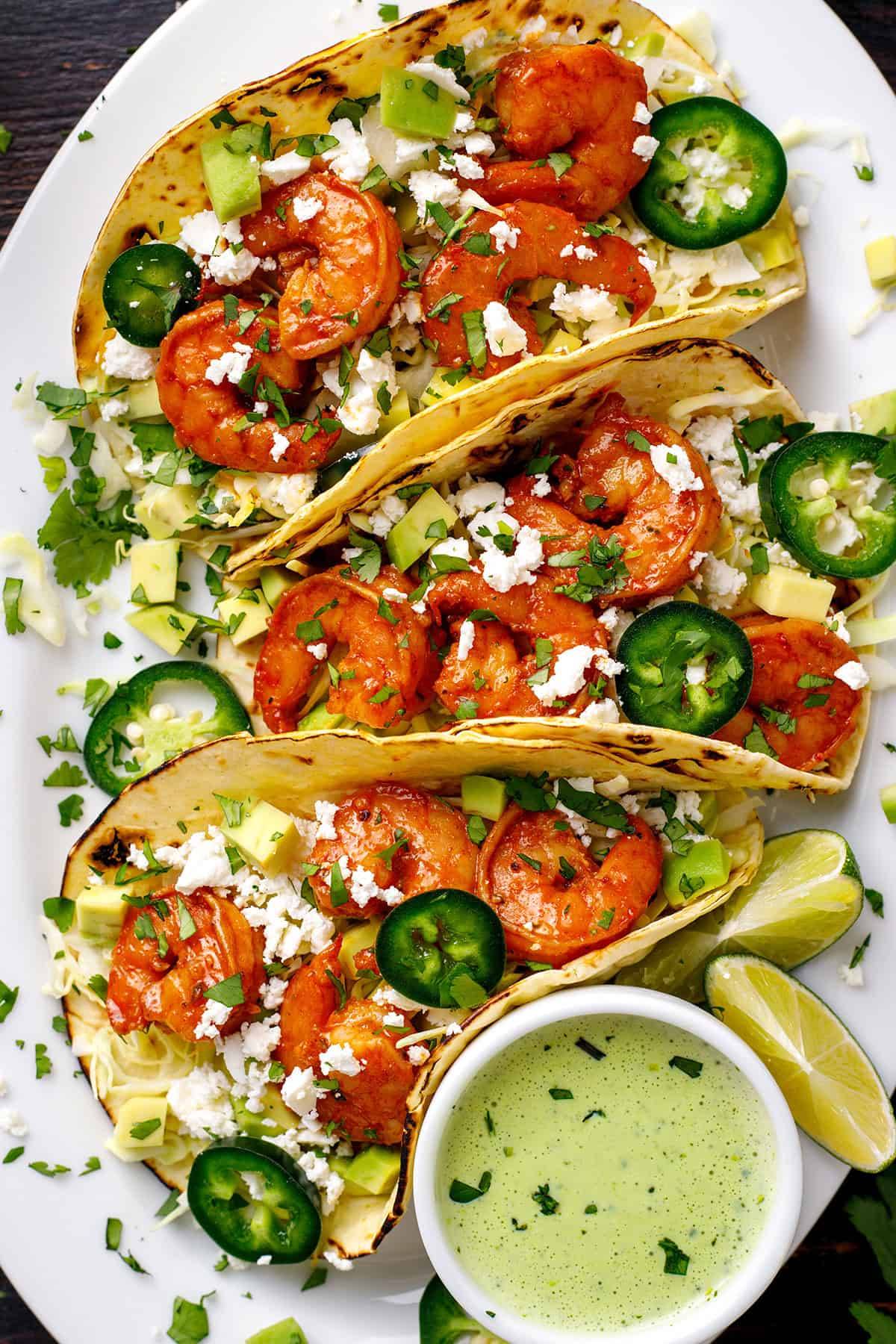Shrimp Tacos with Cilantro-Lime Crema, crisp cabbage, avocado, cilantro, feta, and jalapeño.