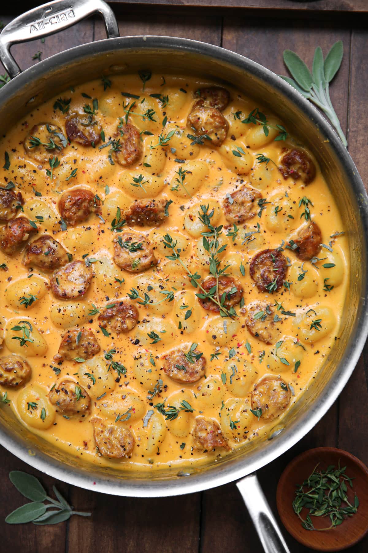Creamy Butternut Squash Gnocchi with Sausage, Thyme, and Sage in a stainless steel pan.