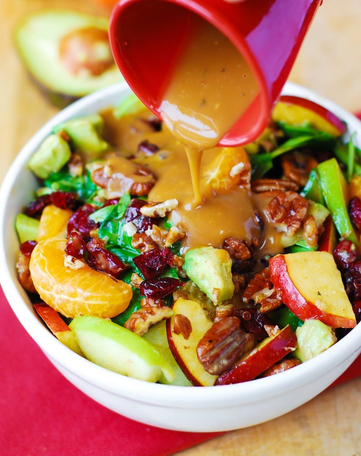 Apple Cranberry Spinach Salad with Pecans, Avocados (and Balsamic Vinaigrette Dressing) in a white bowl.