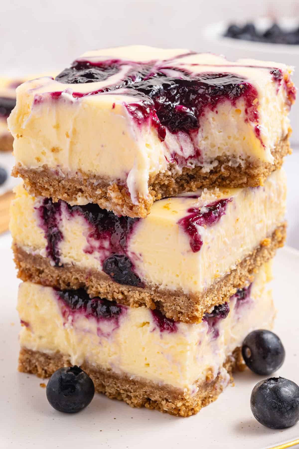 Blueberry Cheesecake Bars (3 bars stacked on one another) on a white plate.