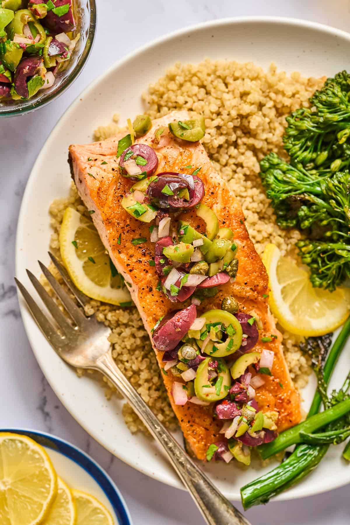 Pan-Seared Salmon with Chunky Olives, Capers, and Lemon Sauce, Quinoa, and Broccoli Rabe - on a plate.