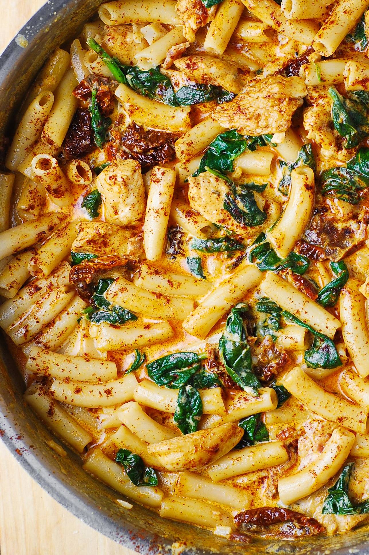 Asiago Chicken Pasta with Sun-Dried Tomatoes and Spinach in a stainless steel pan.